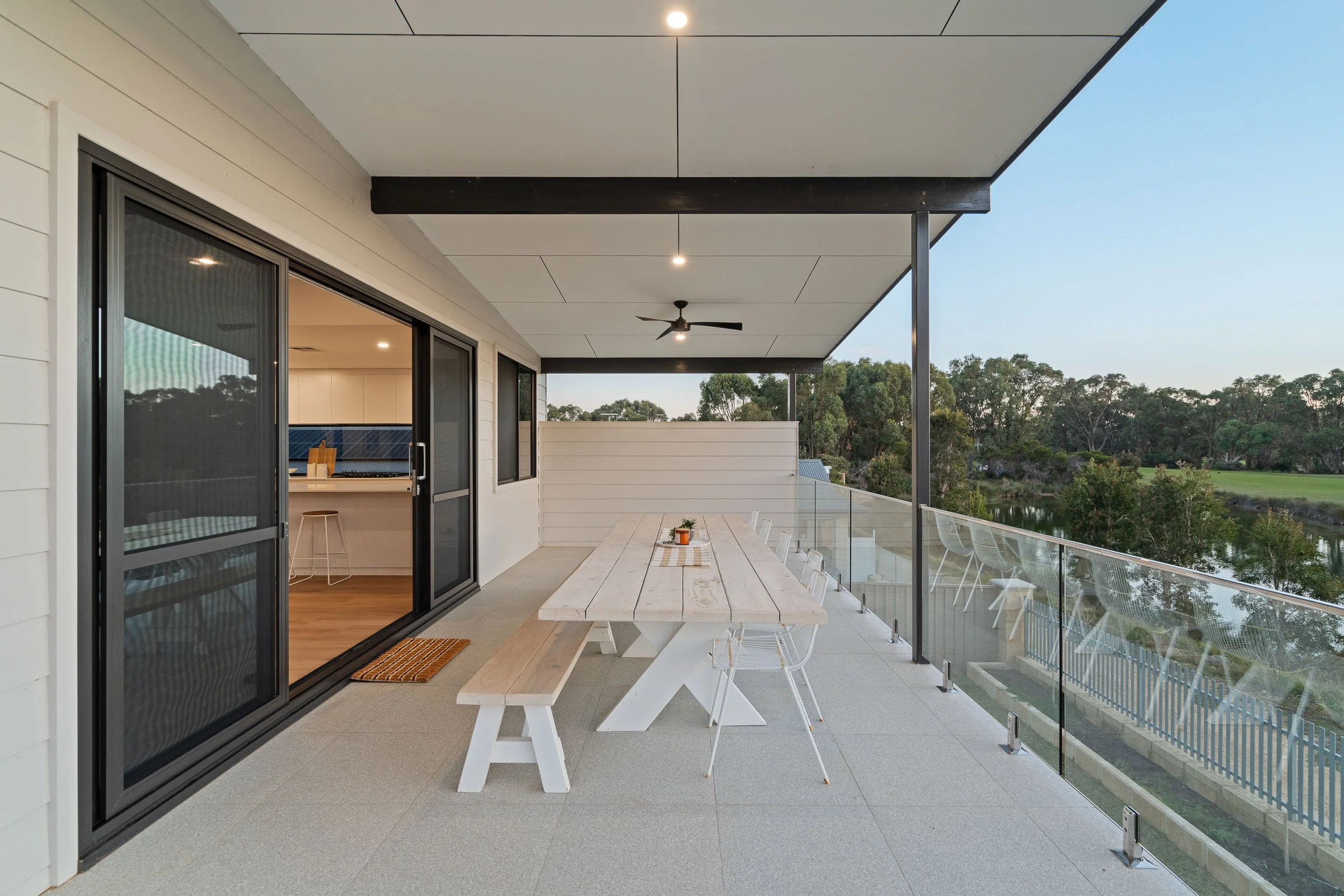 Spacious covered terrace with outdoor seating, a barbecue and glass balustrades.
