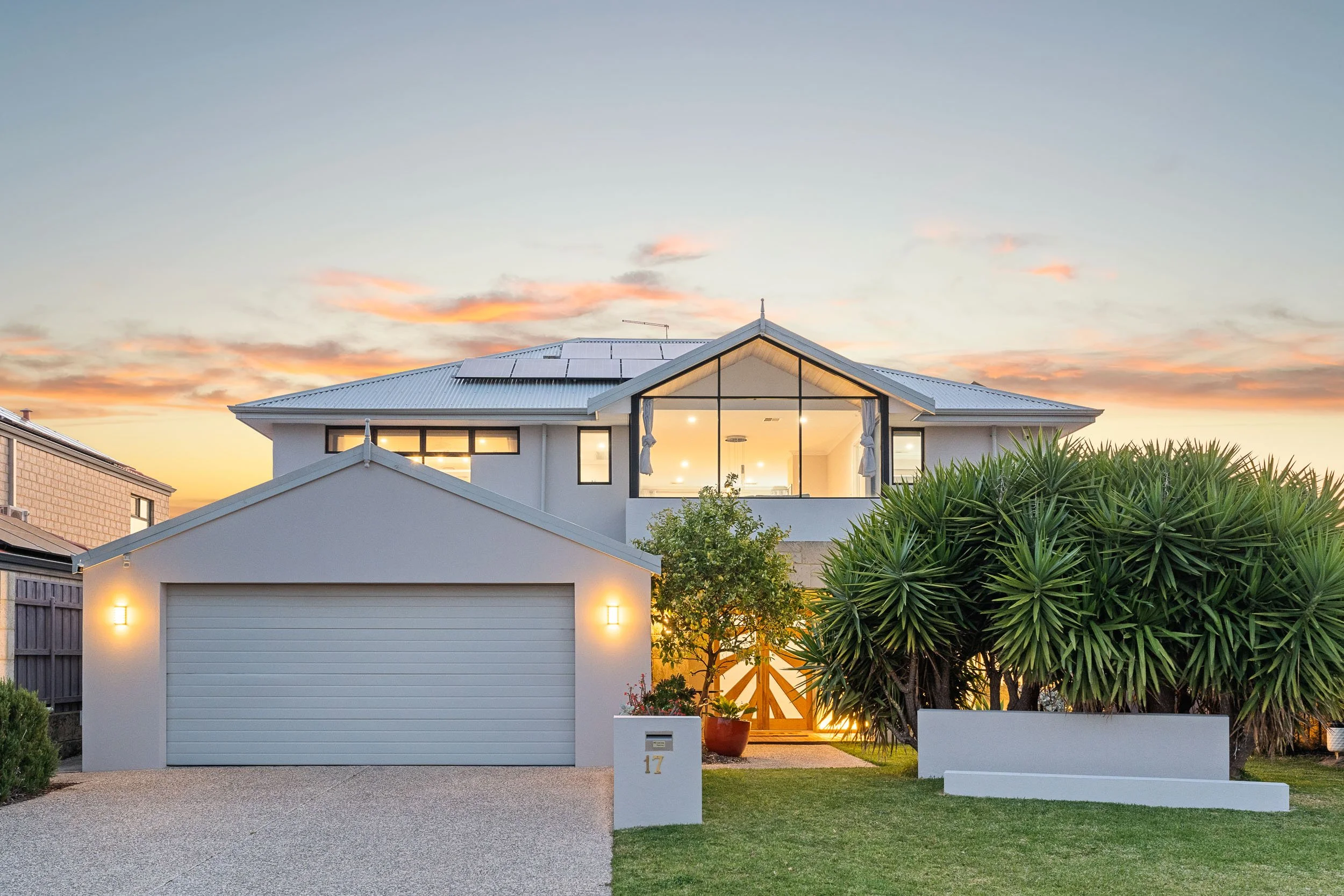 Contemporary two-storey home at dusk with a glazed upper gable and landscaped frontage.