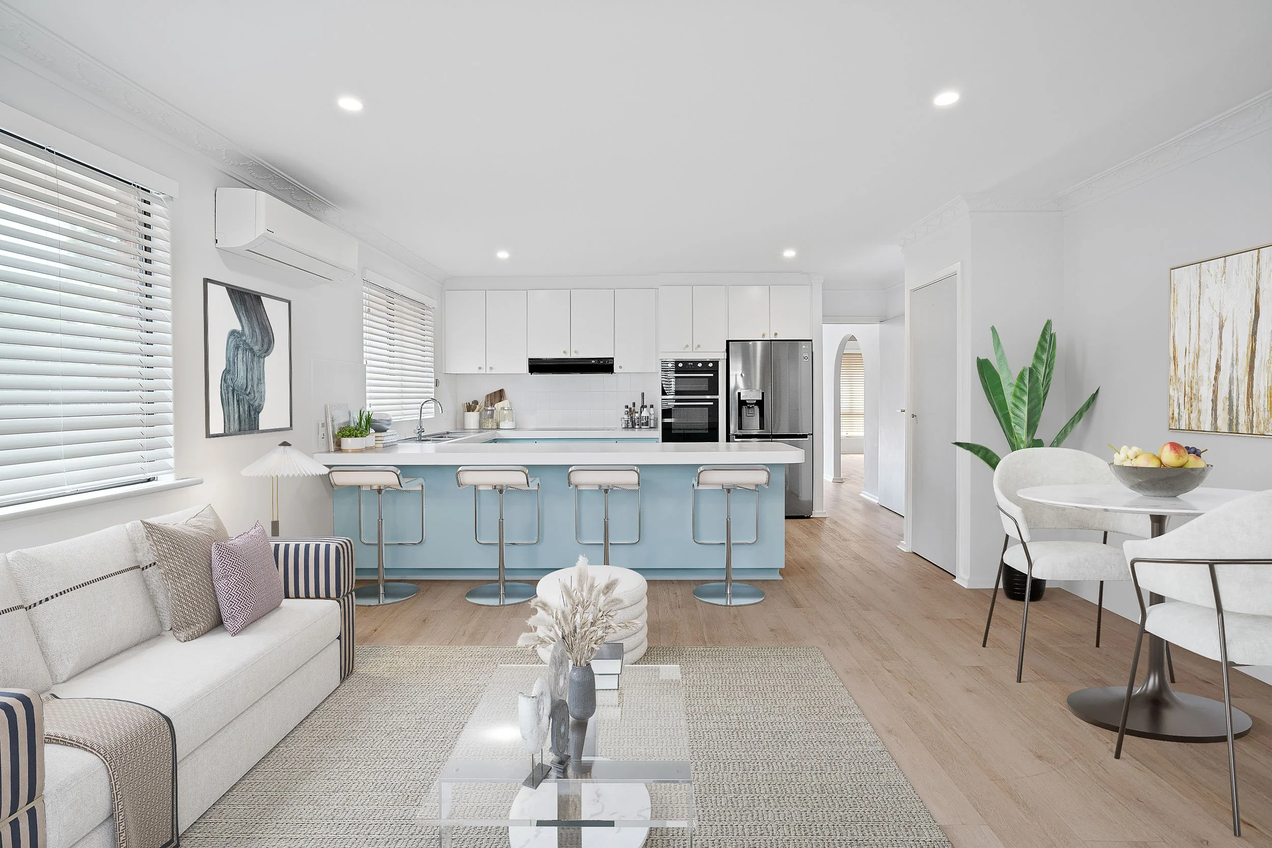 Virtually staged open-plan living area adjoining a kitchen with pale blue cabinetry.