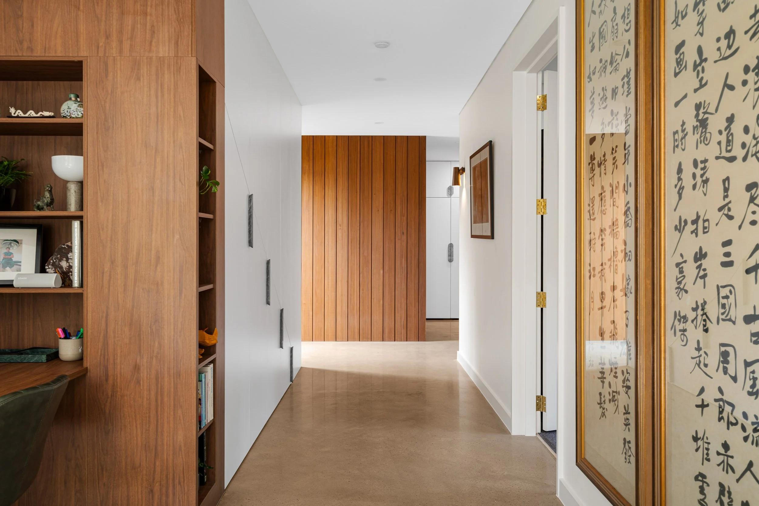Light-filled hallway with timber joinery, polished flooring and framed calligraphy panels.