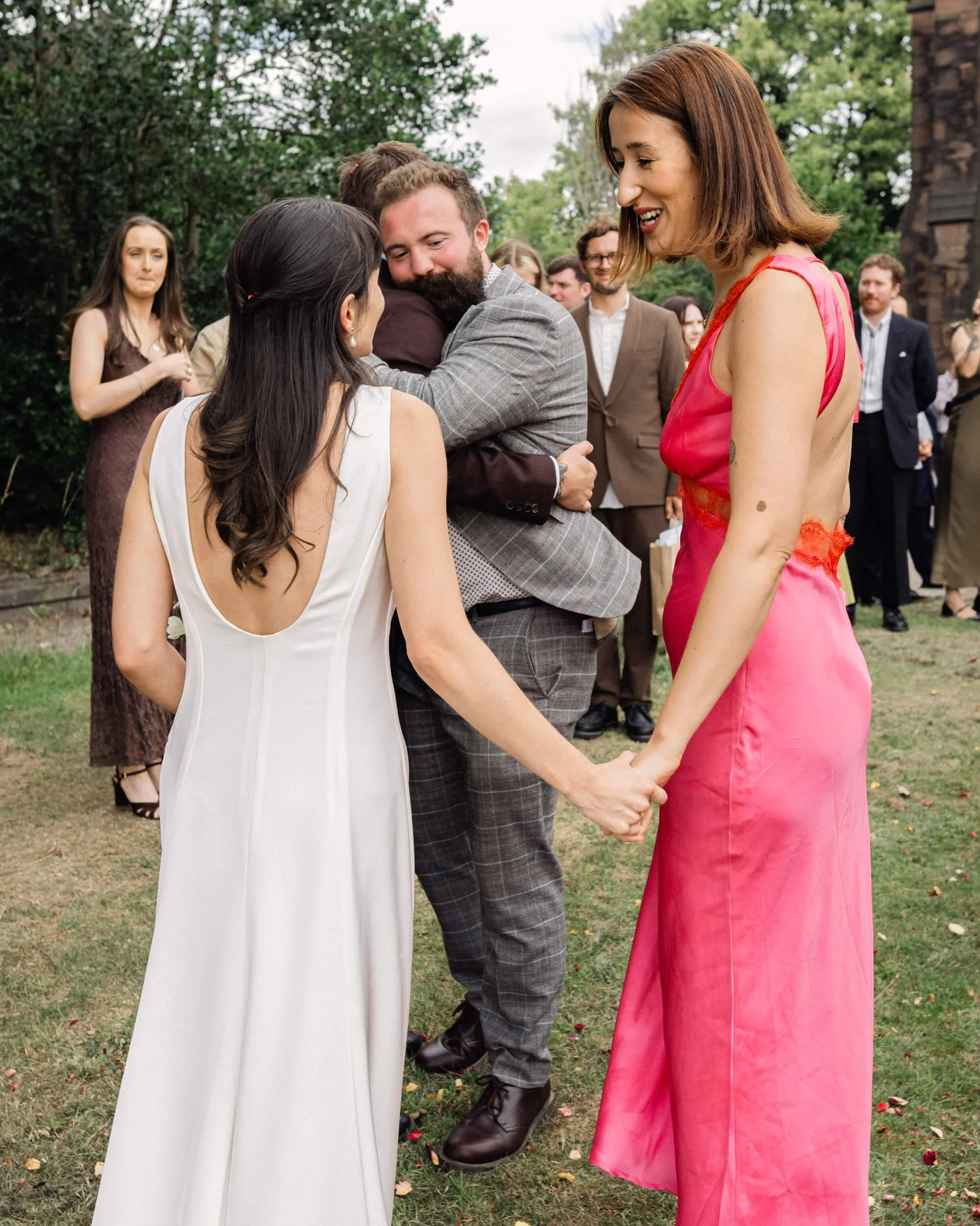 Bride and a wedding guest hold each other's hand as they talk outside the church