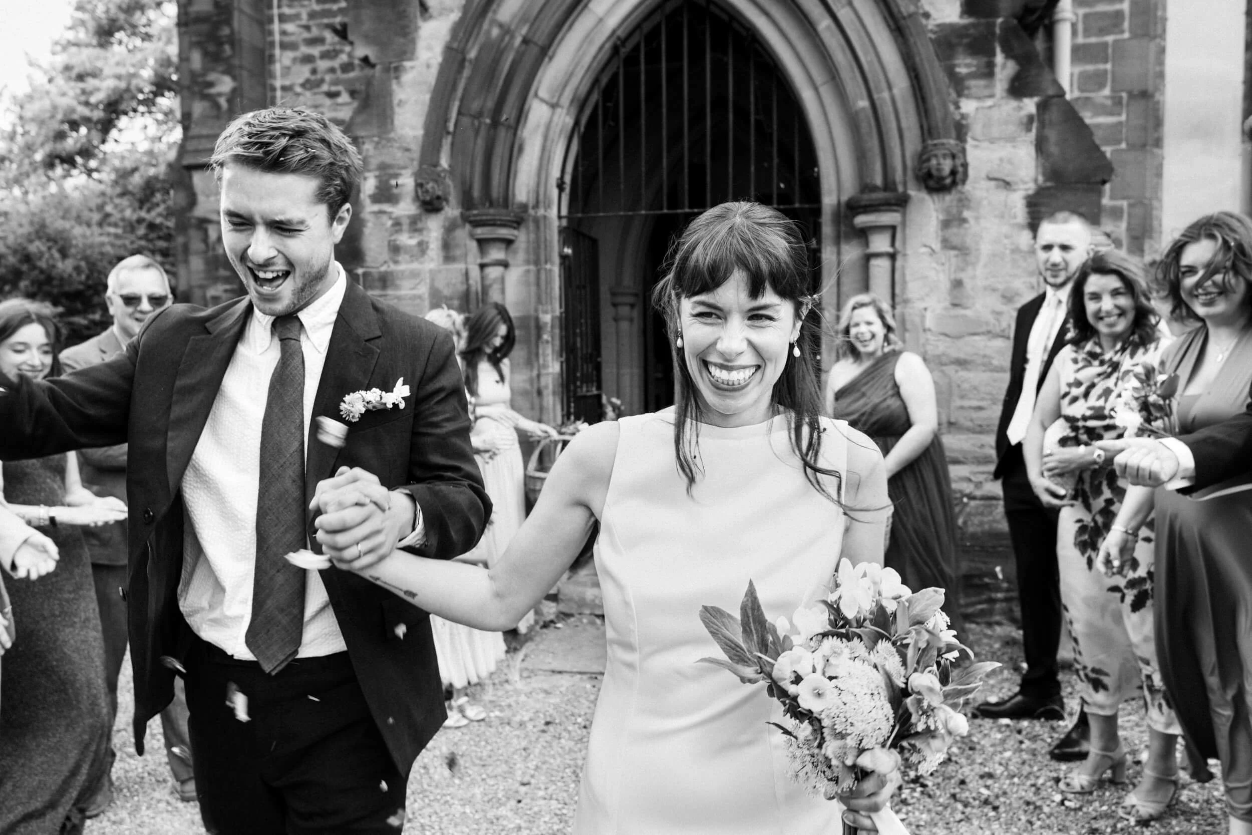 Bride and Groom smile while walking past their family and friends throwing confetti