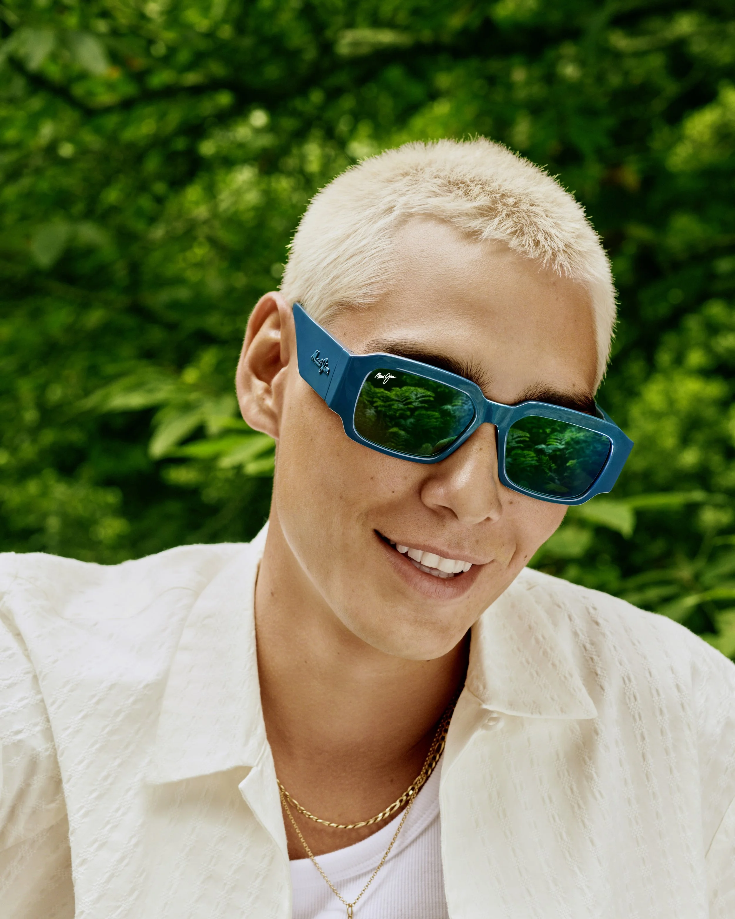 person with blond hair, sunglasses and green nature background