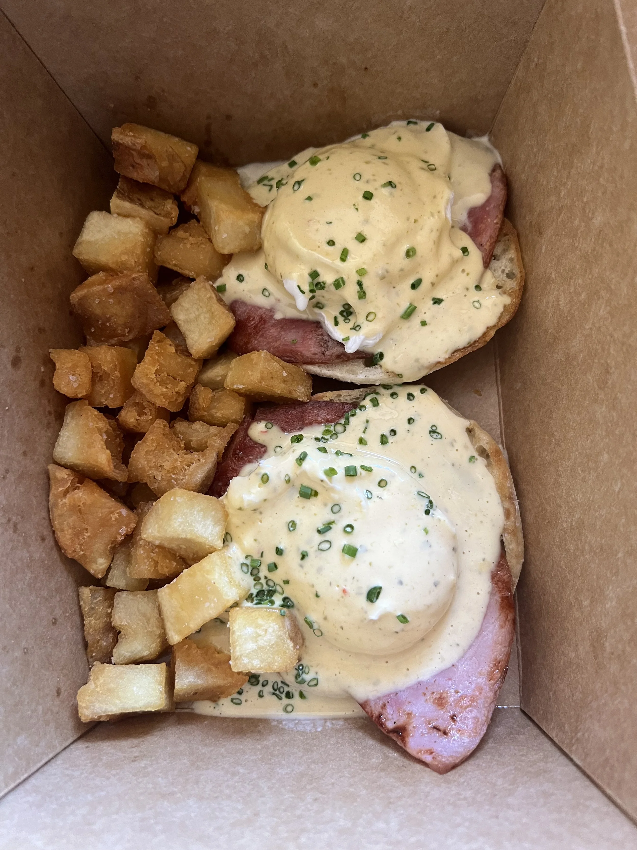 Eggs benedict and home fried in brown box