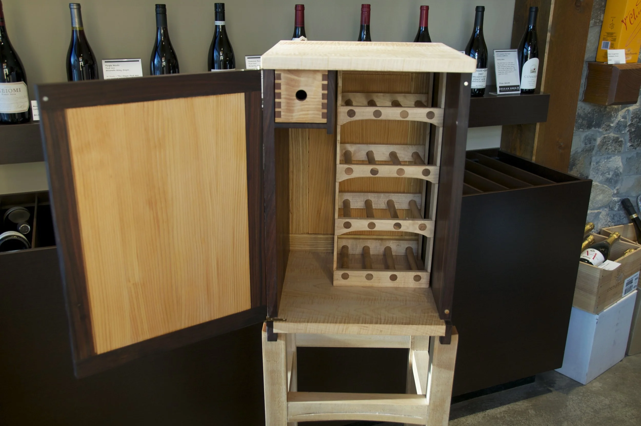 Open wine cabinet with built-in bottle rack and storage space, displayed in a wine store.