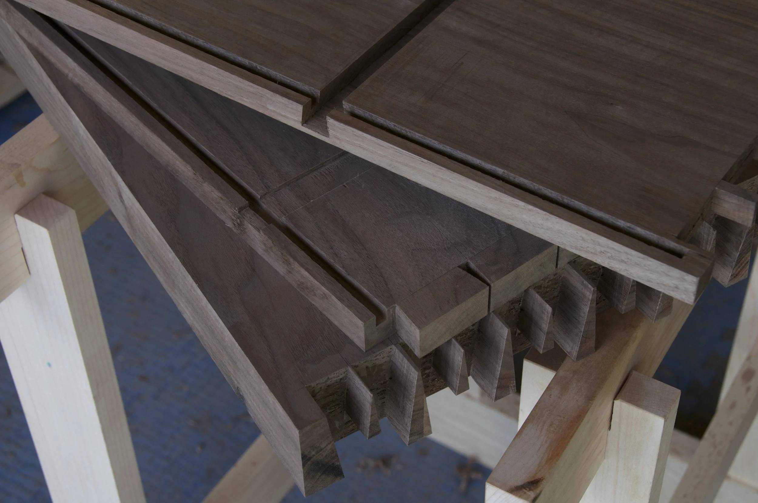 Multiple wooden planks on a worktable in a woodworking shop.