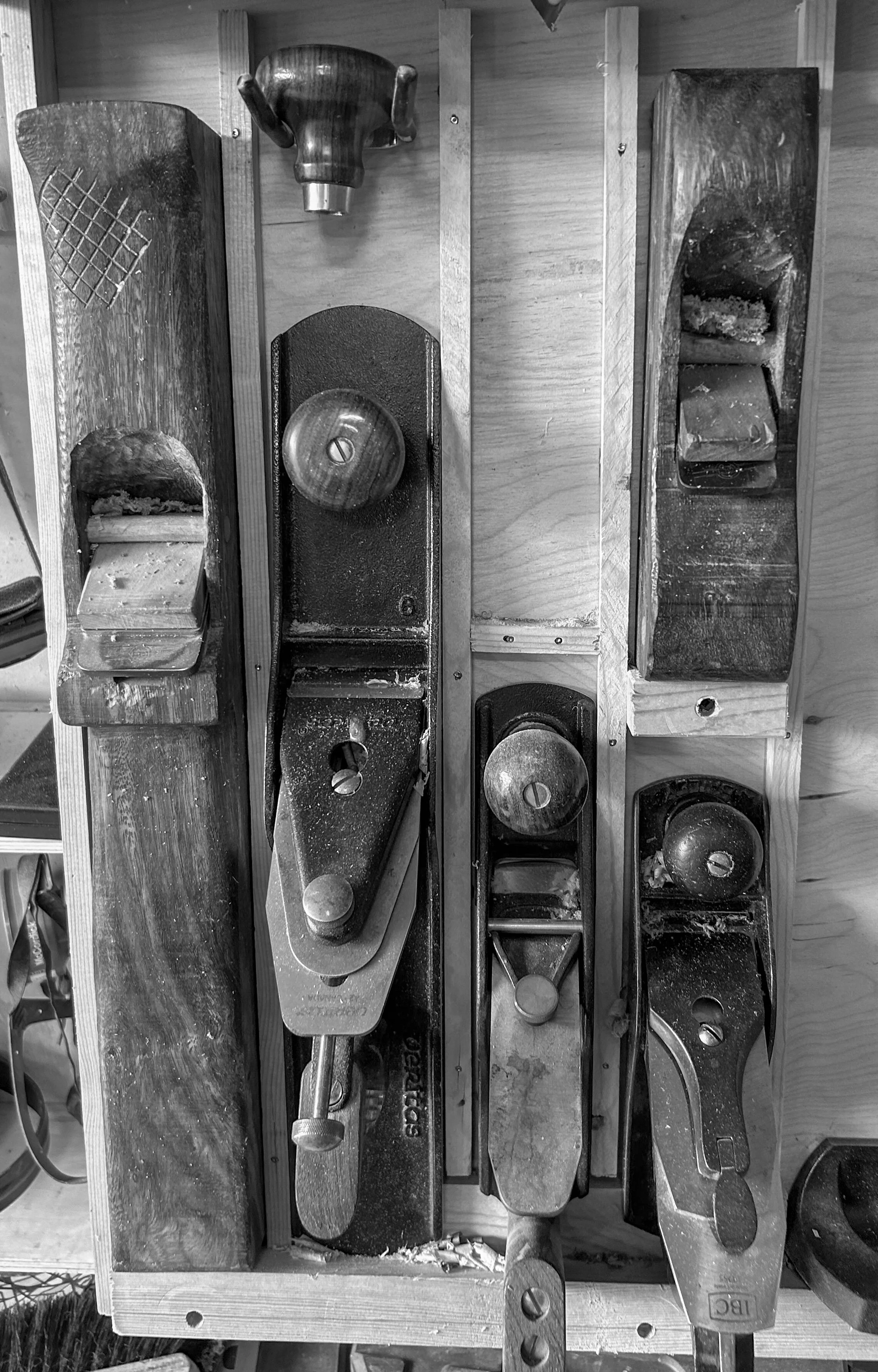 Six woodworking hand planes arranged on a wooden workbench.