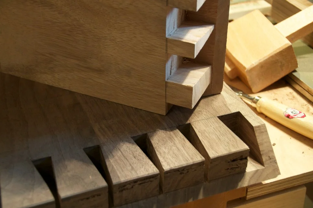 Close-up of wooden pieces being assembled, showing interlocking notches on the edges for a woodworking project.