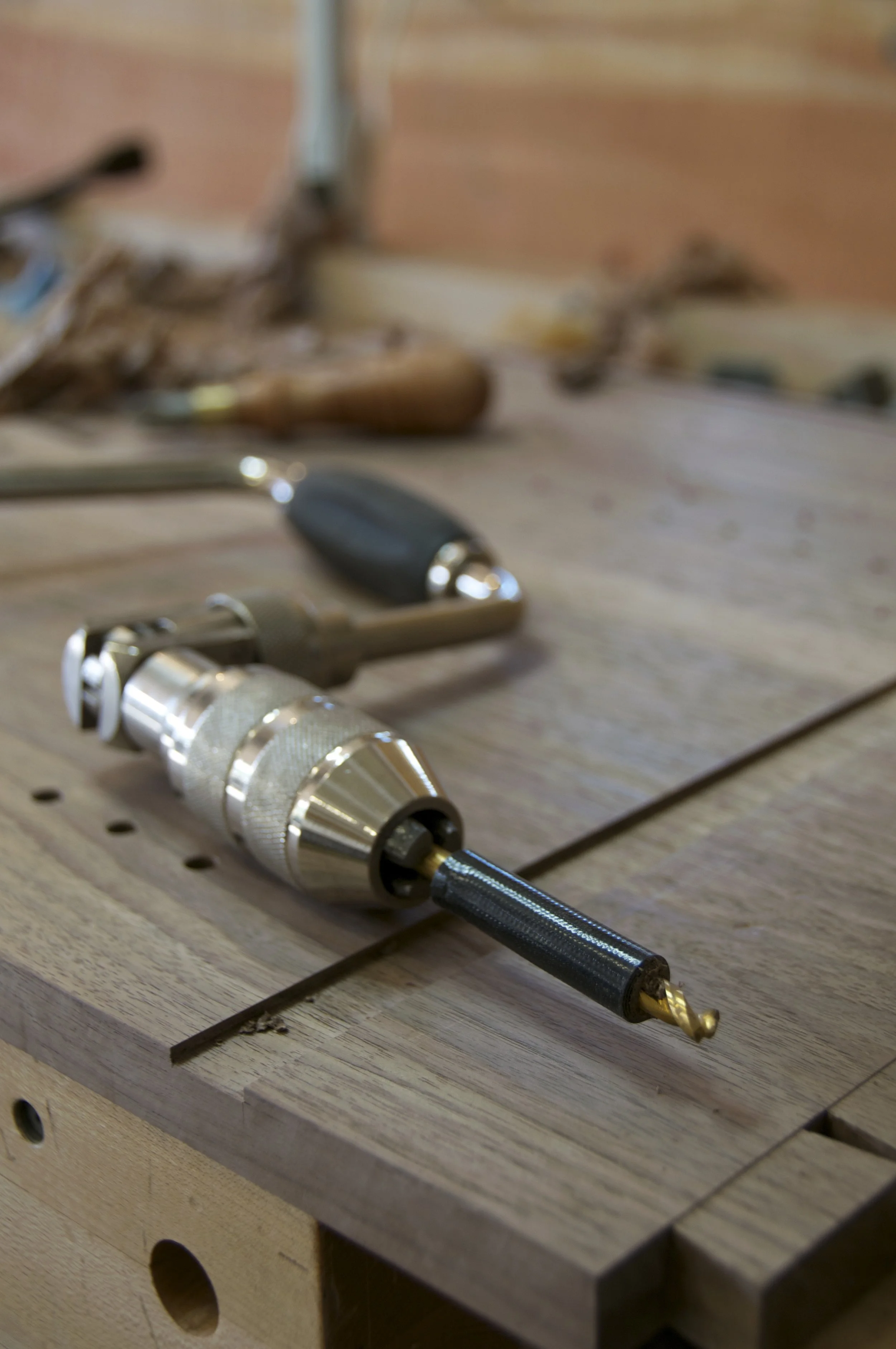 Close-up of a woodworking workbench with a cordless drill, chisel, and woodworking tools