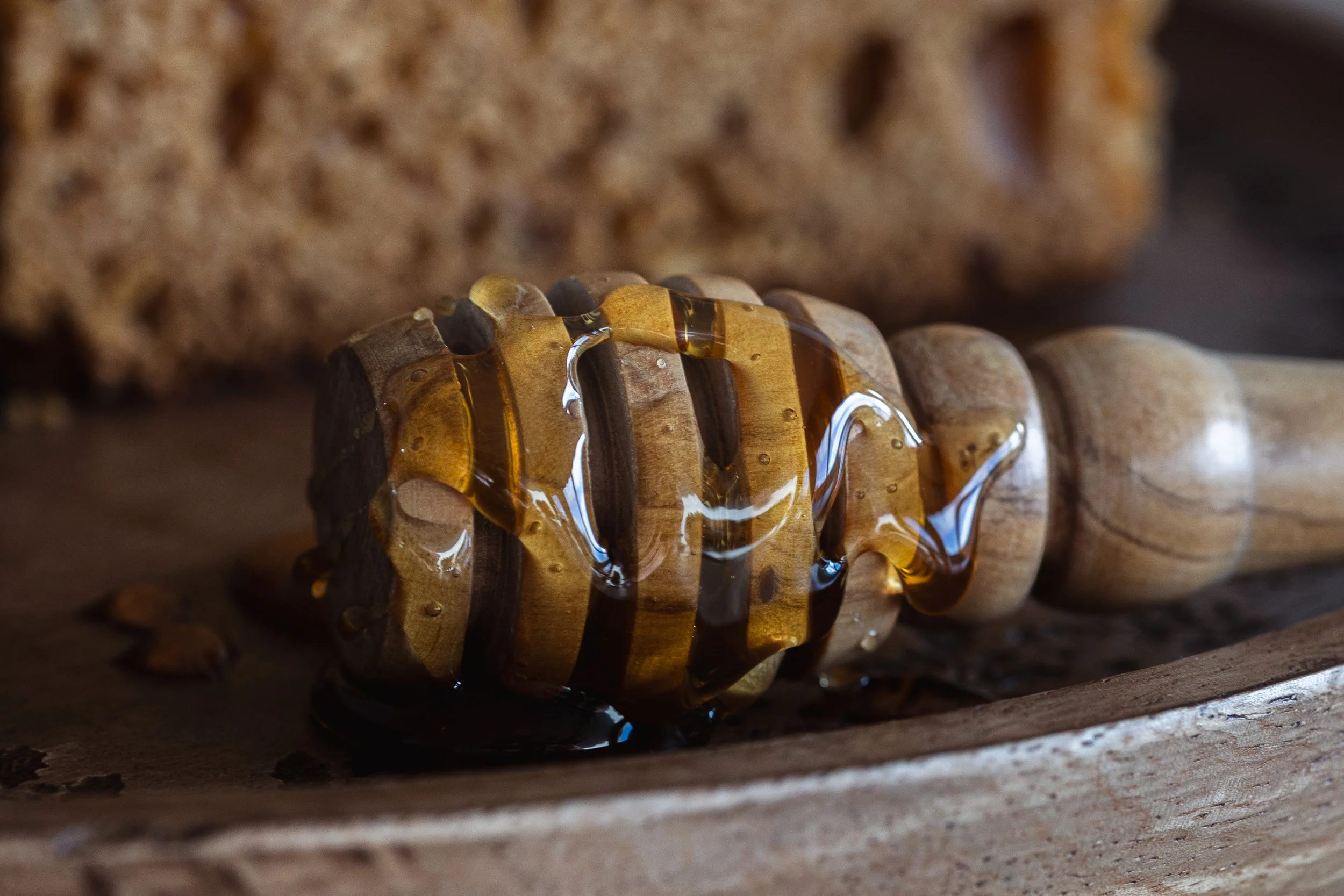 Une cuillère en bois avec du miel coulant dessus, posé sur une surface en bois.