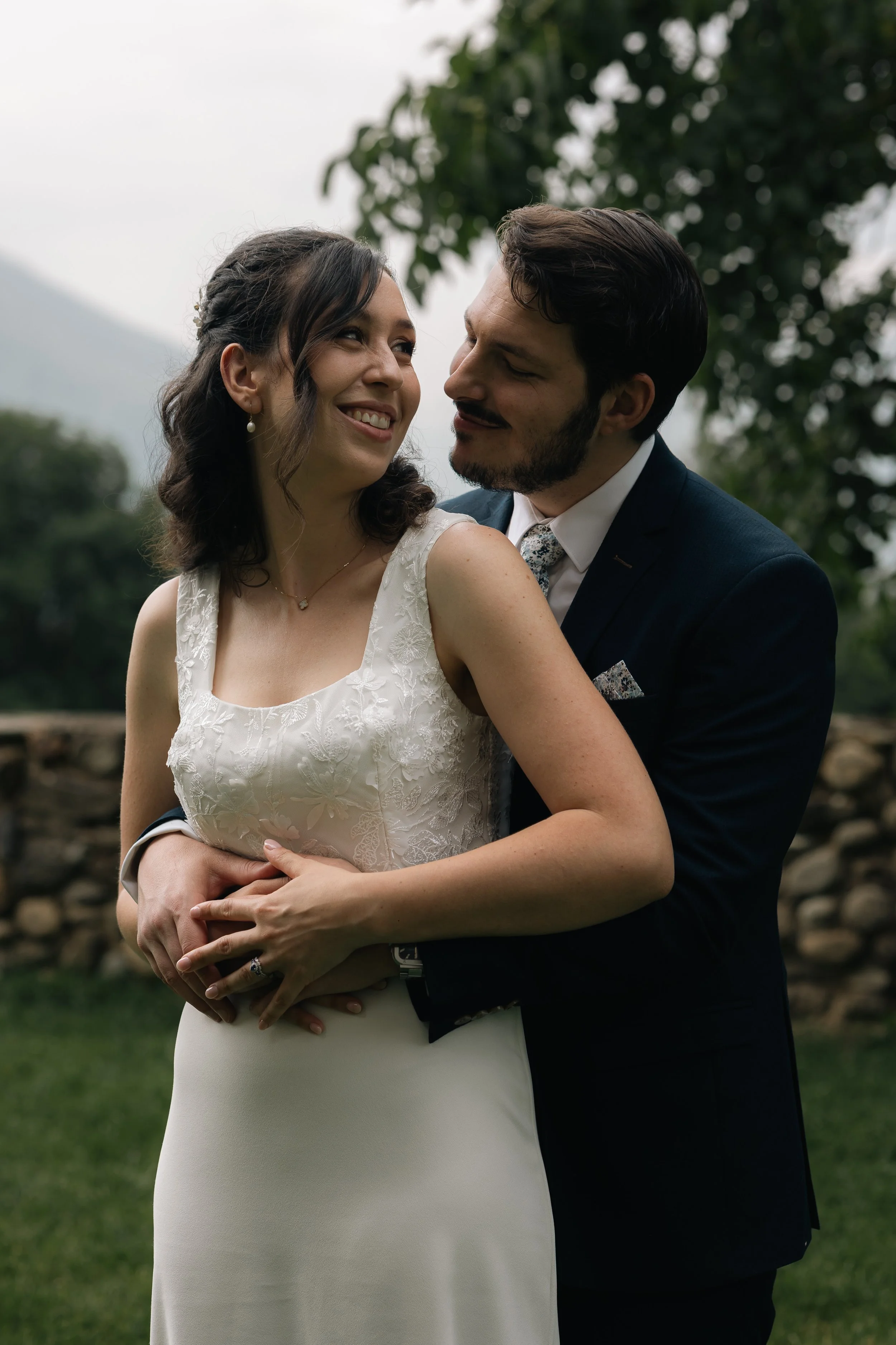 Un couple en costume de mariage s'embrasse dans un jardin verdoyant.