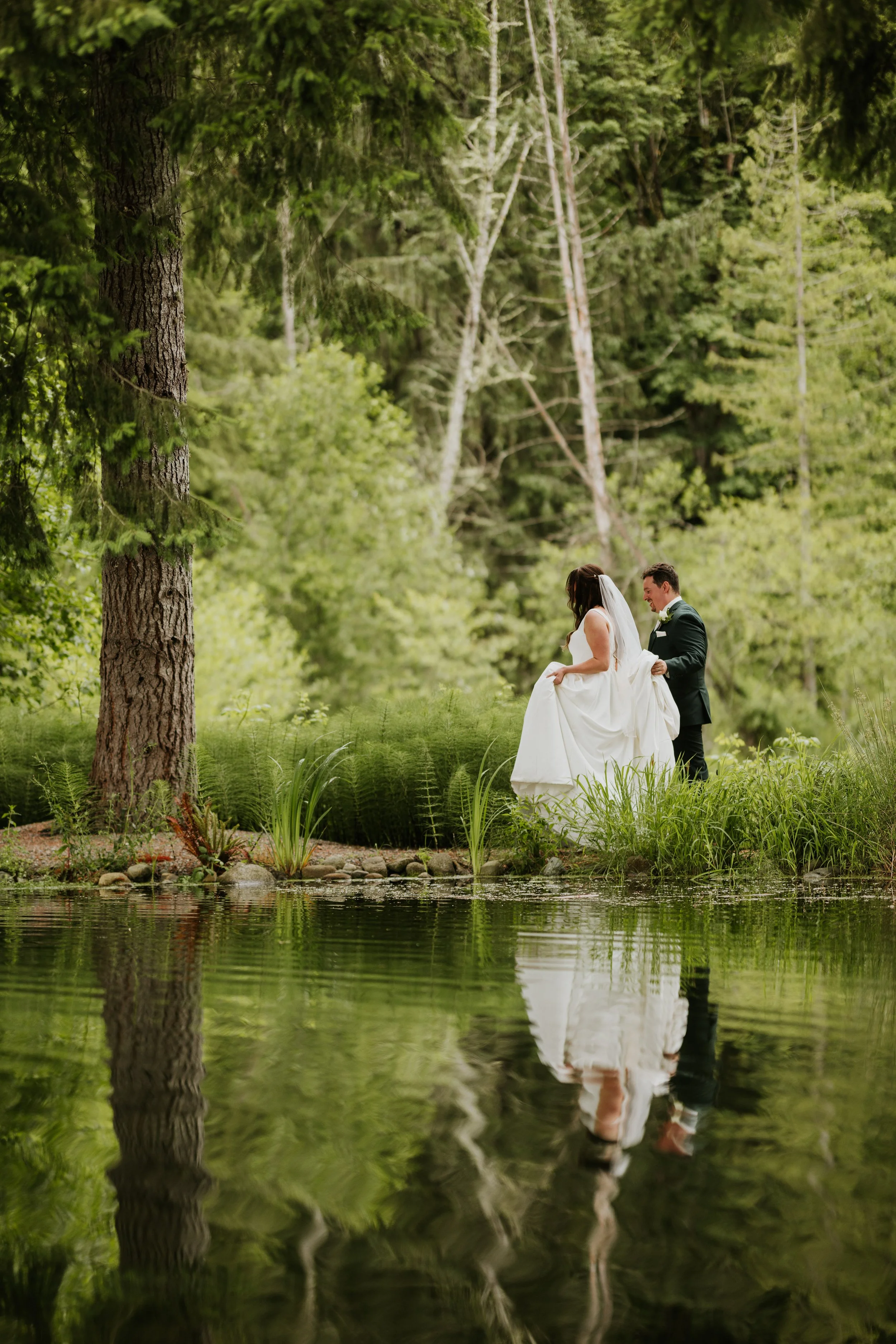 Group of seven people talking and drinking wine or cocktails around a fire pit on an outdoor patio with trees and greenery in the background.