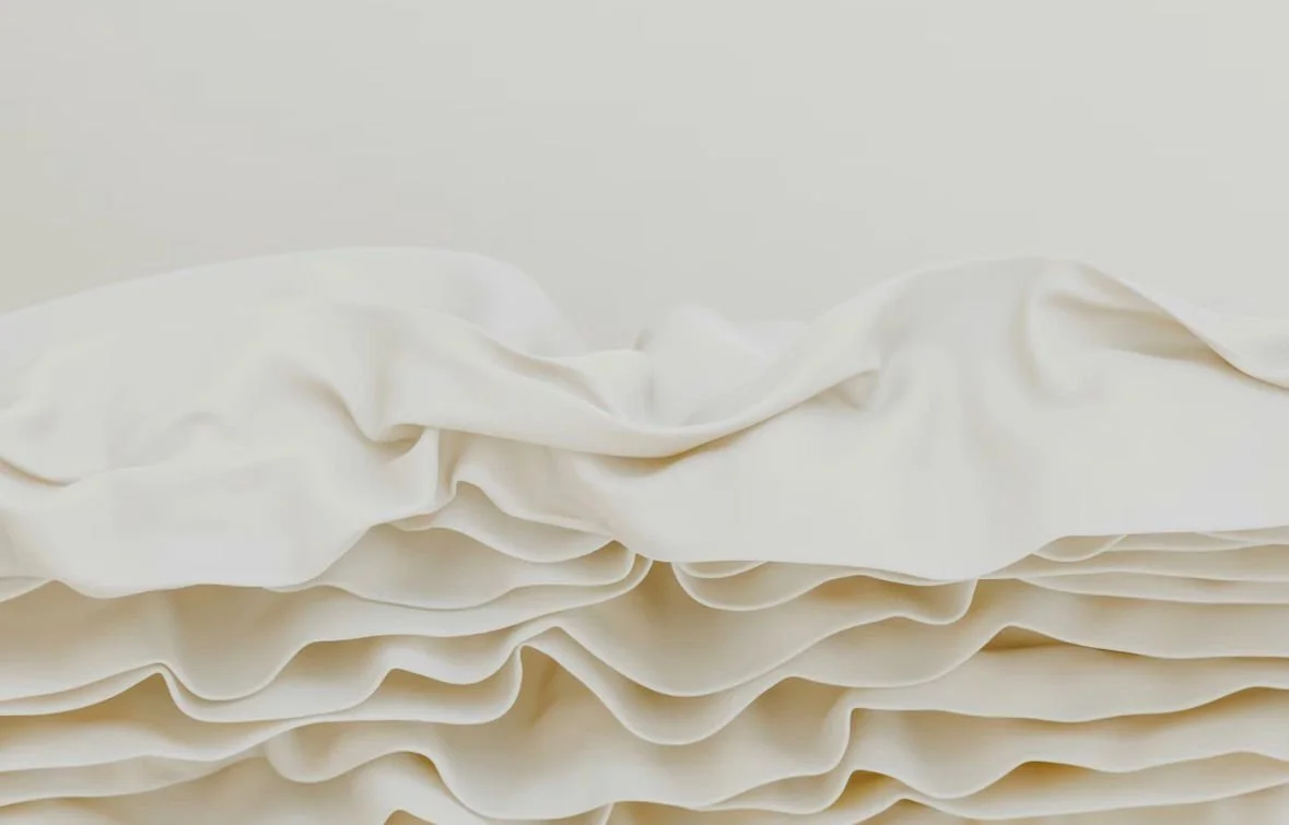 White 100% linen tablecloth folded with soft ruffles and natural fabric texture visible, styled in a relaxed and rustic finish. For our tablecloth Tradition sip & paint