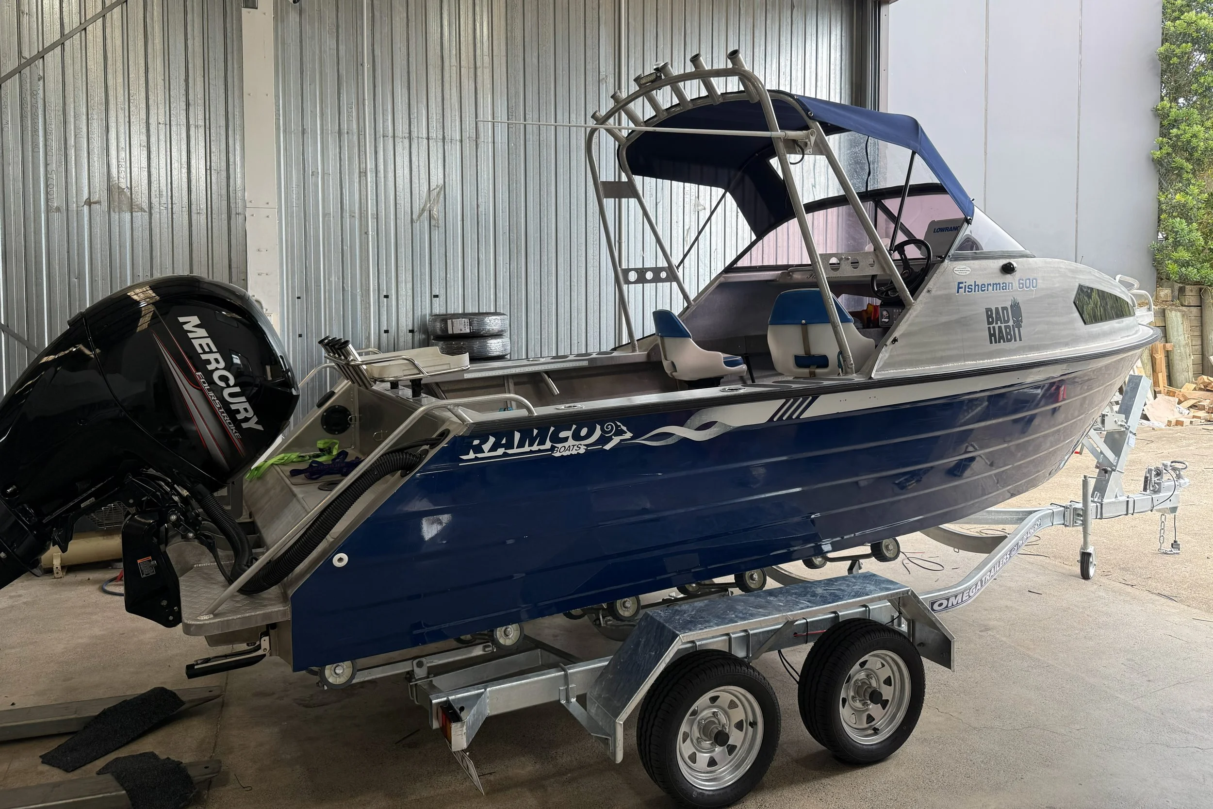 Blue and white speedboat on a dual-axle trailer inside a garage