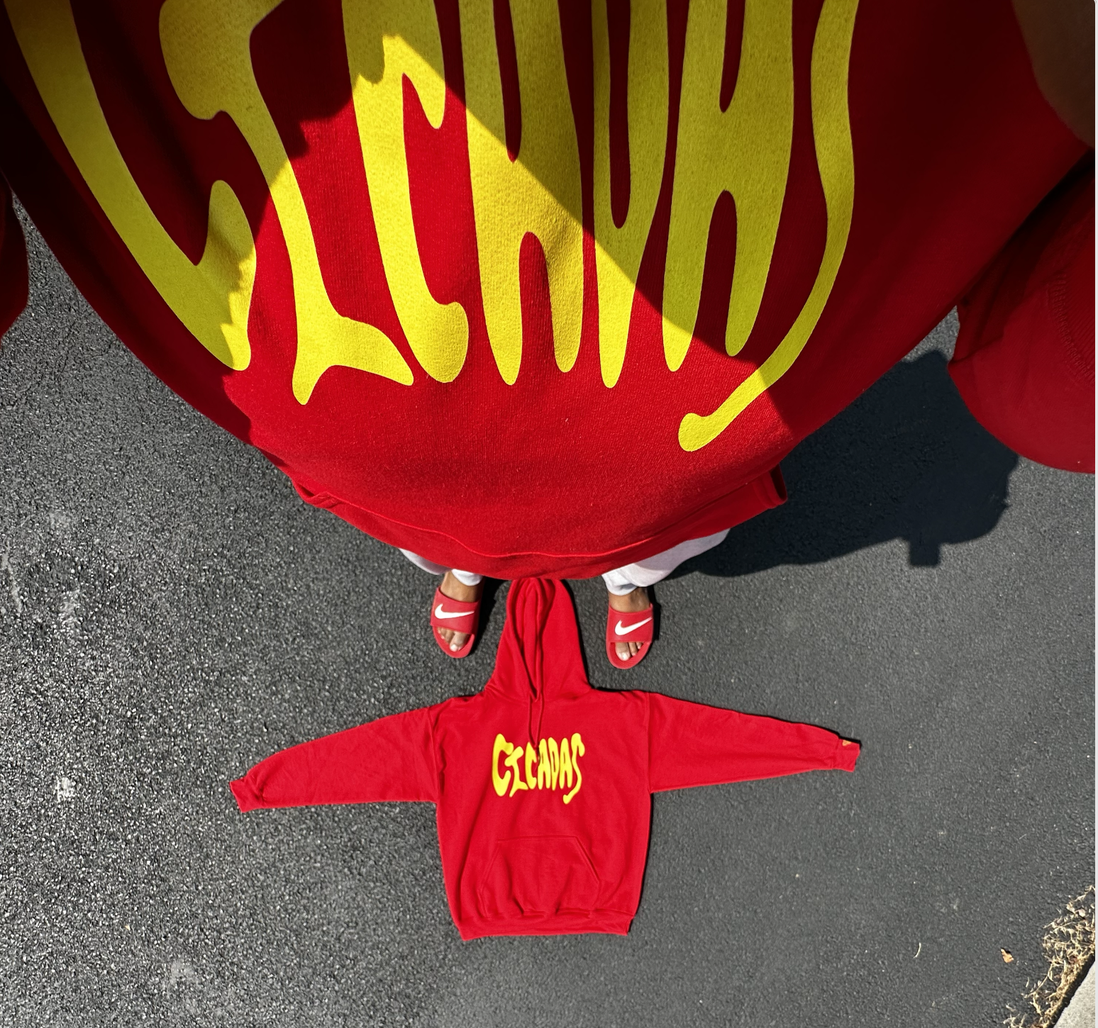 Matching red hoodies with yellow lettering laid out on pavement