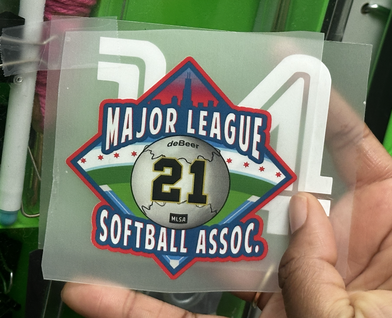 Hand holding a Major League Softball Association patch with the number 21