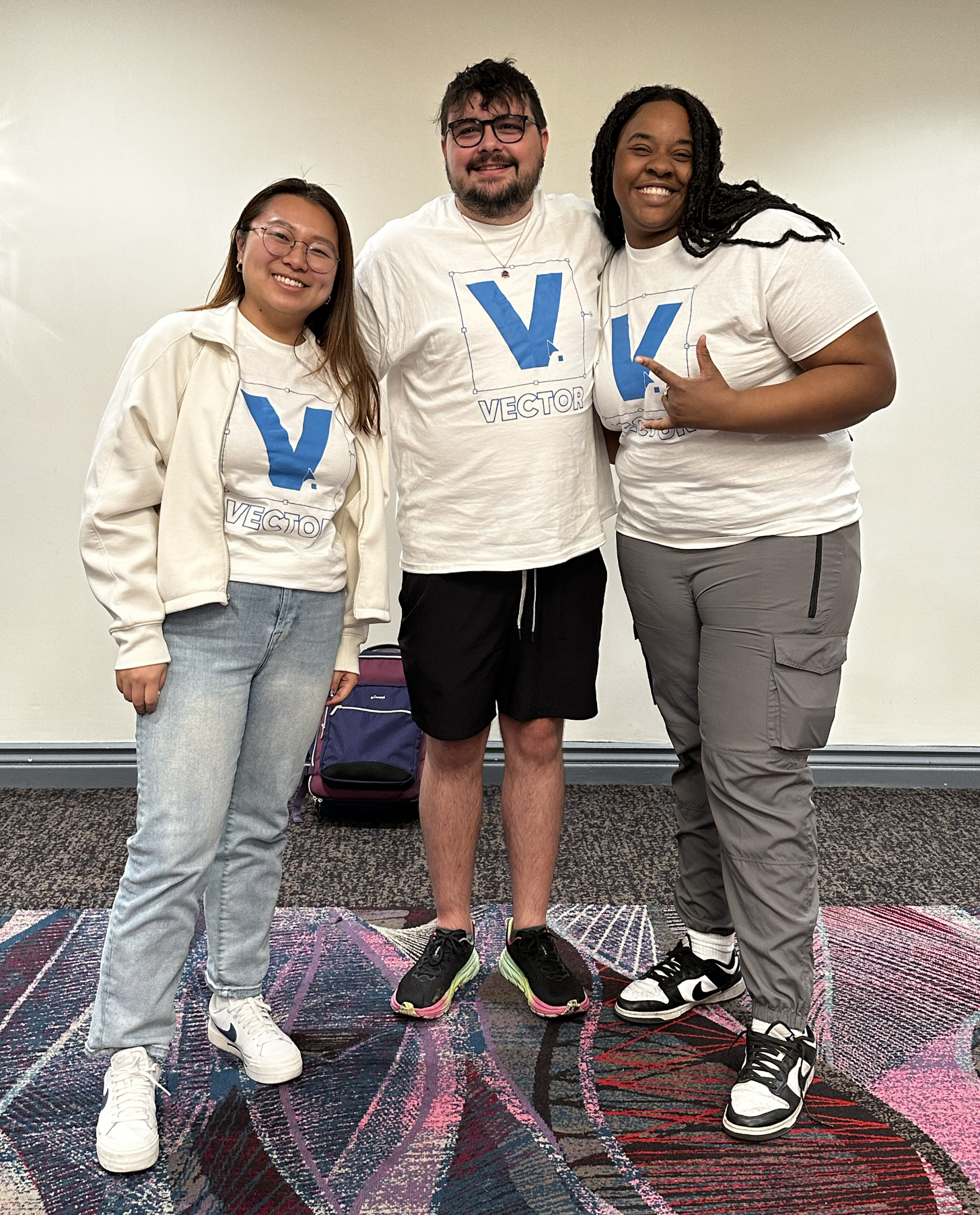 Three people wearing matching custom white shirts with a blue V logo