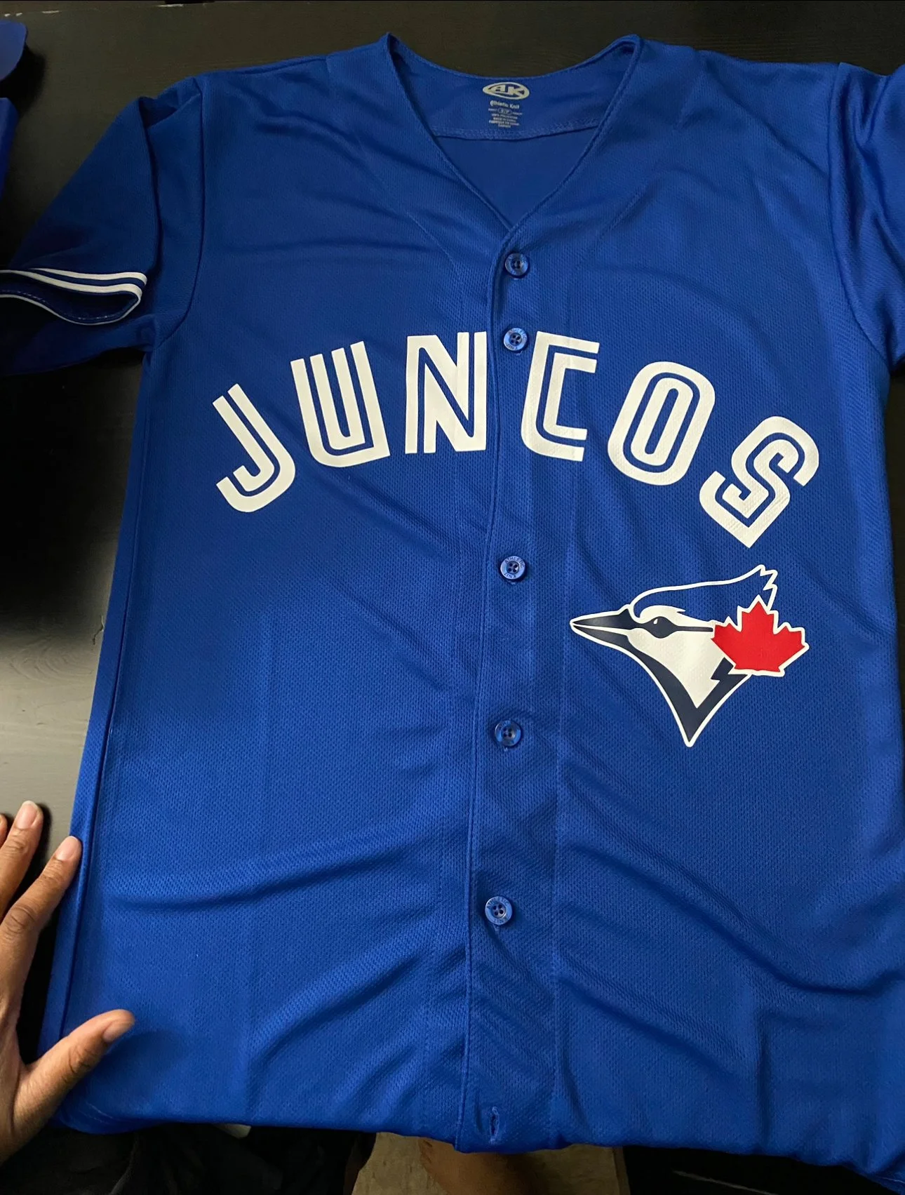 Blue button-up baseball jersey printed with "Juncos" and a blue jay logo