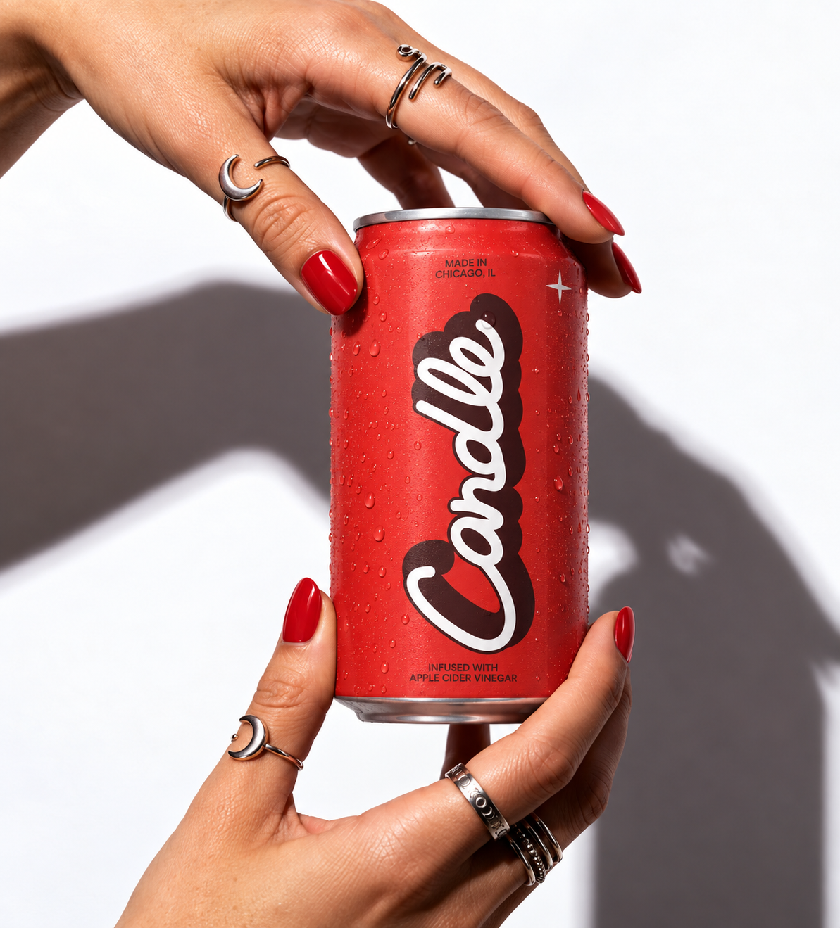 Hands with red nails holding a Candle cherry cola can