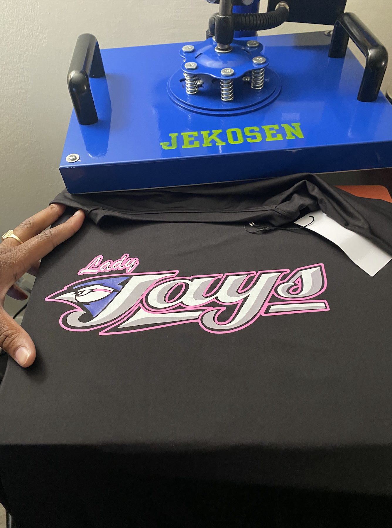 Heat press pressing a Lady Jays tee