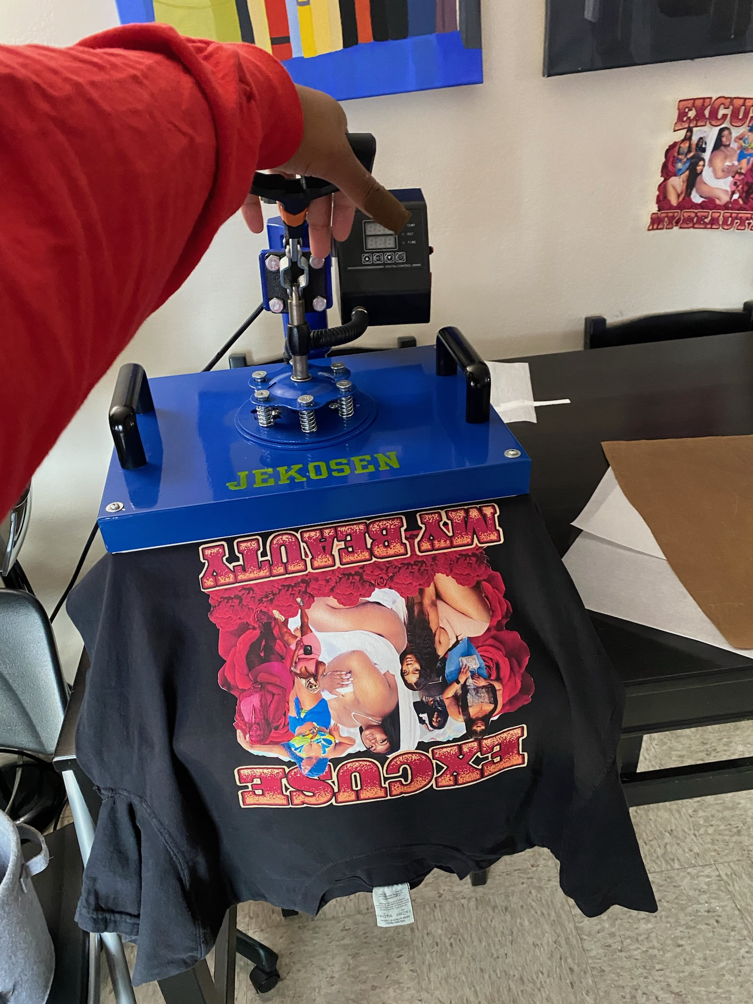 Heat press applying a full-color graphic to a black tee