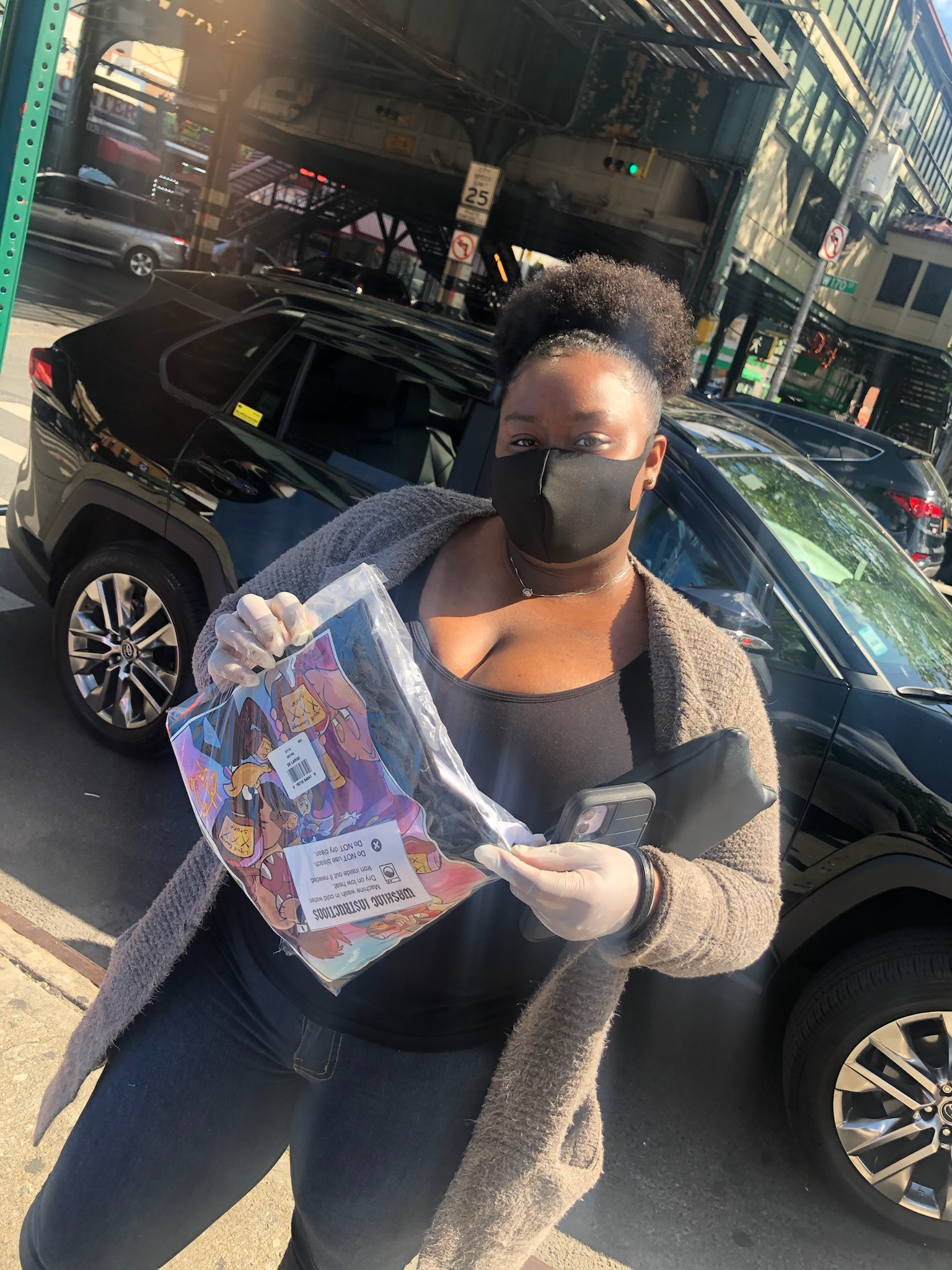 Customer in a face mask holding a custom printed shirt outdoors