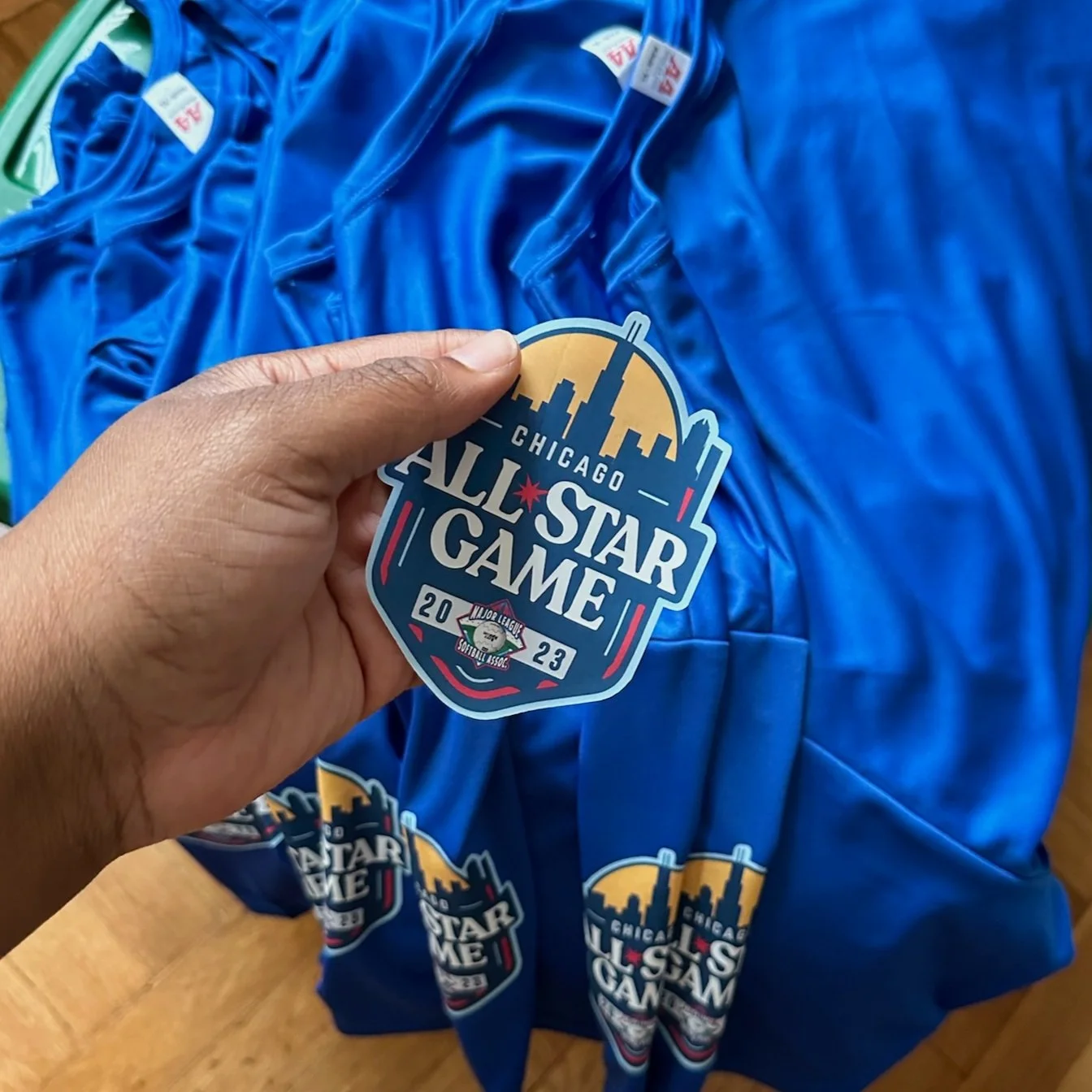 Hand holding a Chicago All-Star Game patch over a stack of blue jerseys
