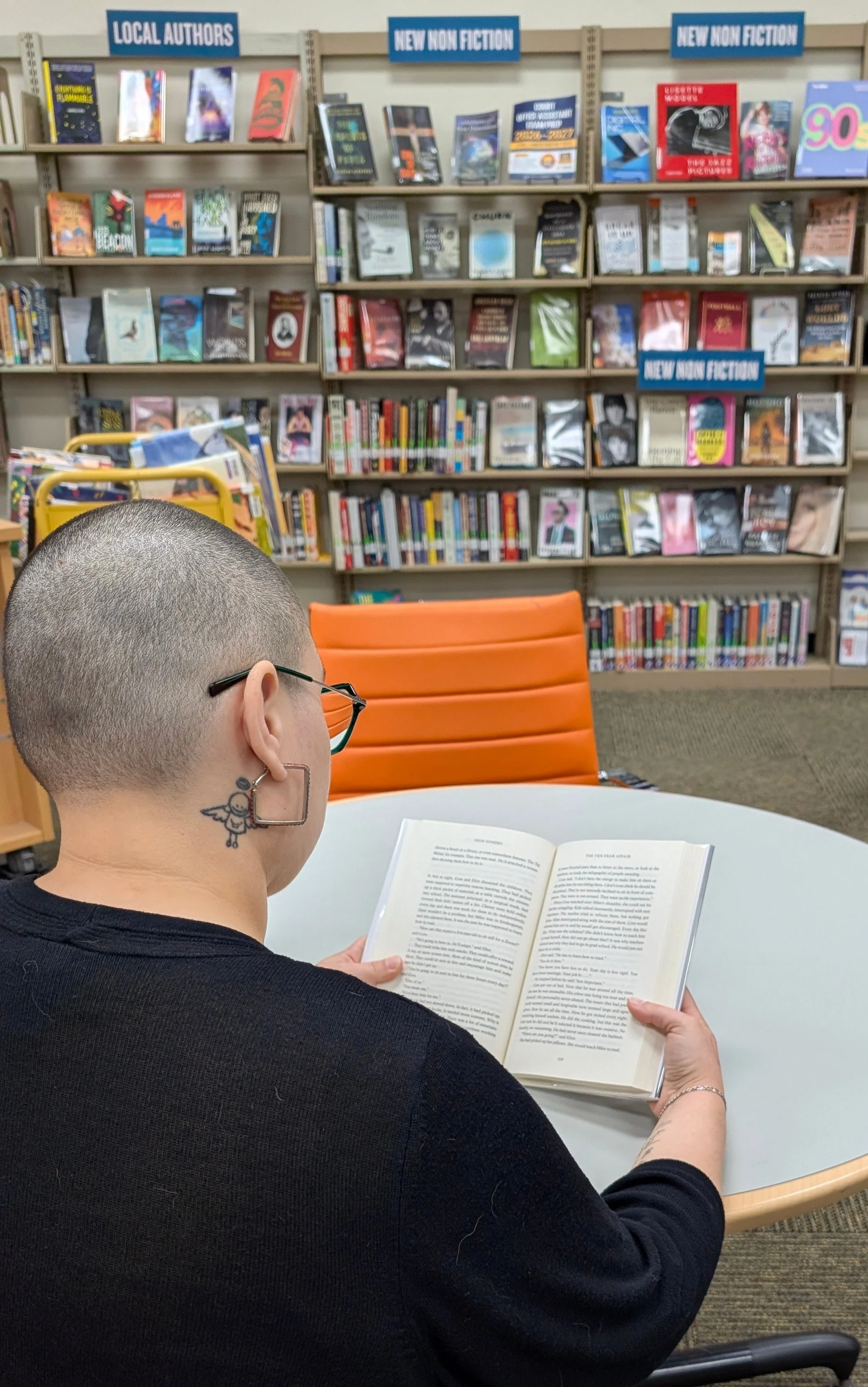 Over the shoulder view of a person reading a book inside the library