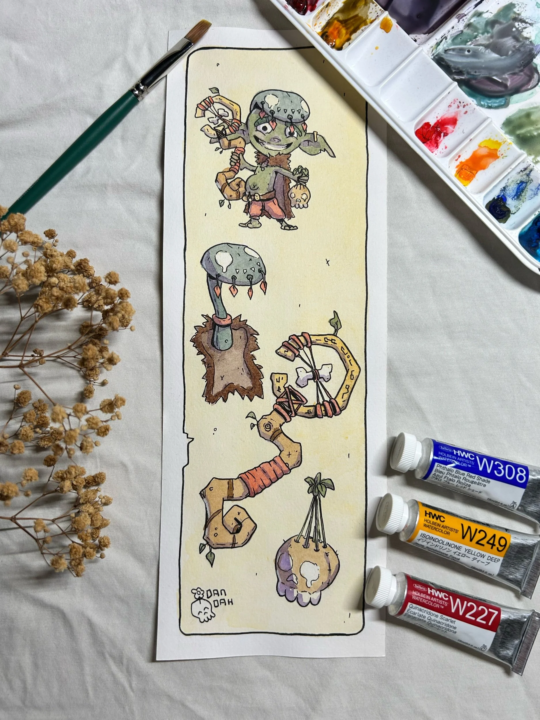 Green goblin witchdoctor with fur cloak, bone staff and hanging skull, ink and watercolor art beside a paint palette.