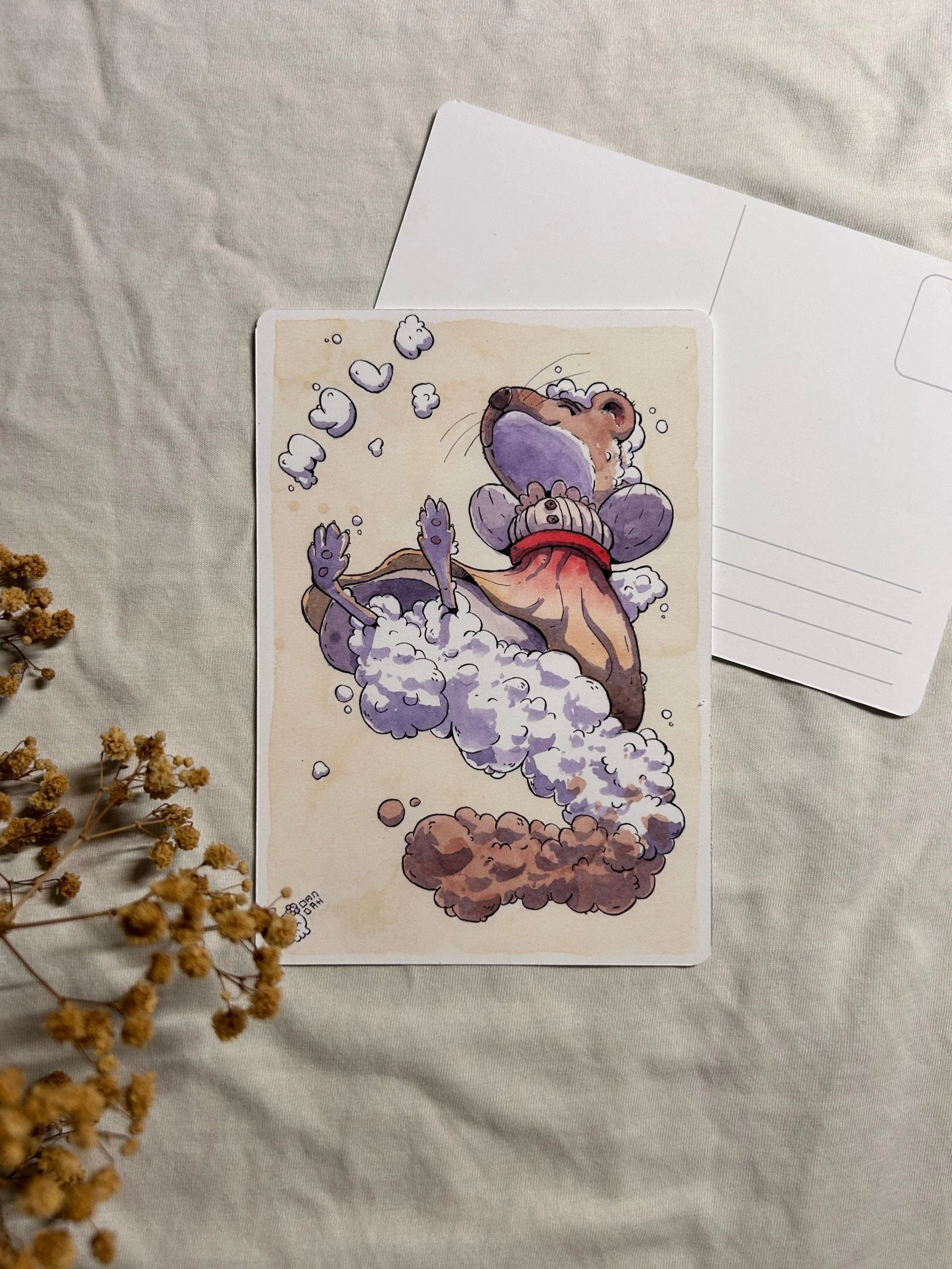 Dreamy weasel resting in soft purple clouds on an A6 postcard, ink and watercolor illustration with dried flowers.