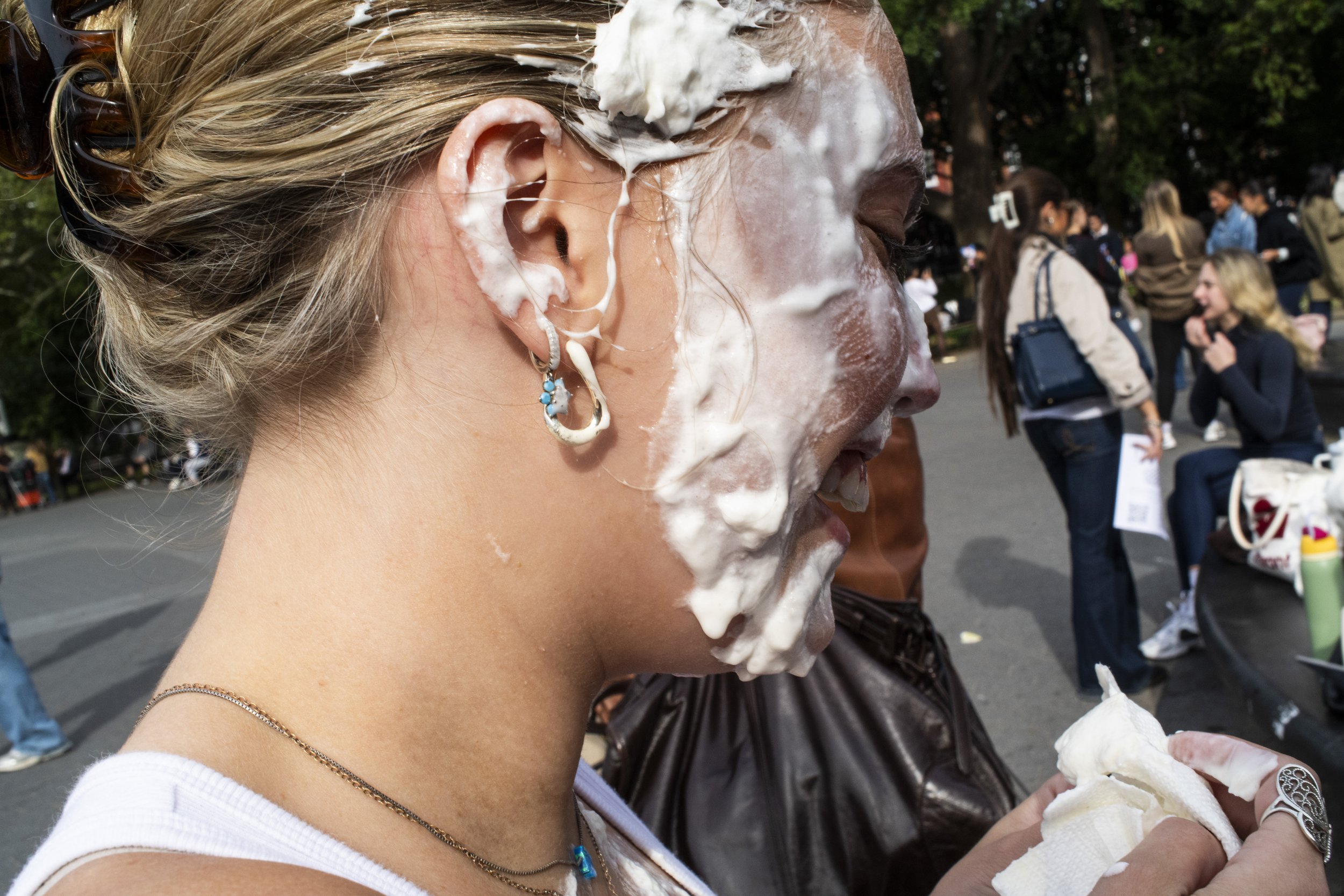 Woman with whipped cream smeared on her face and earrings photographed in Manhattan