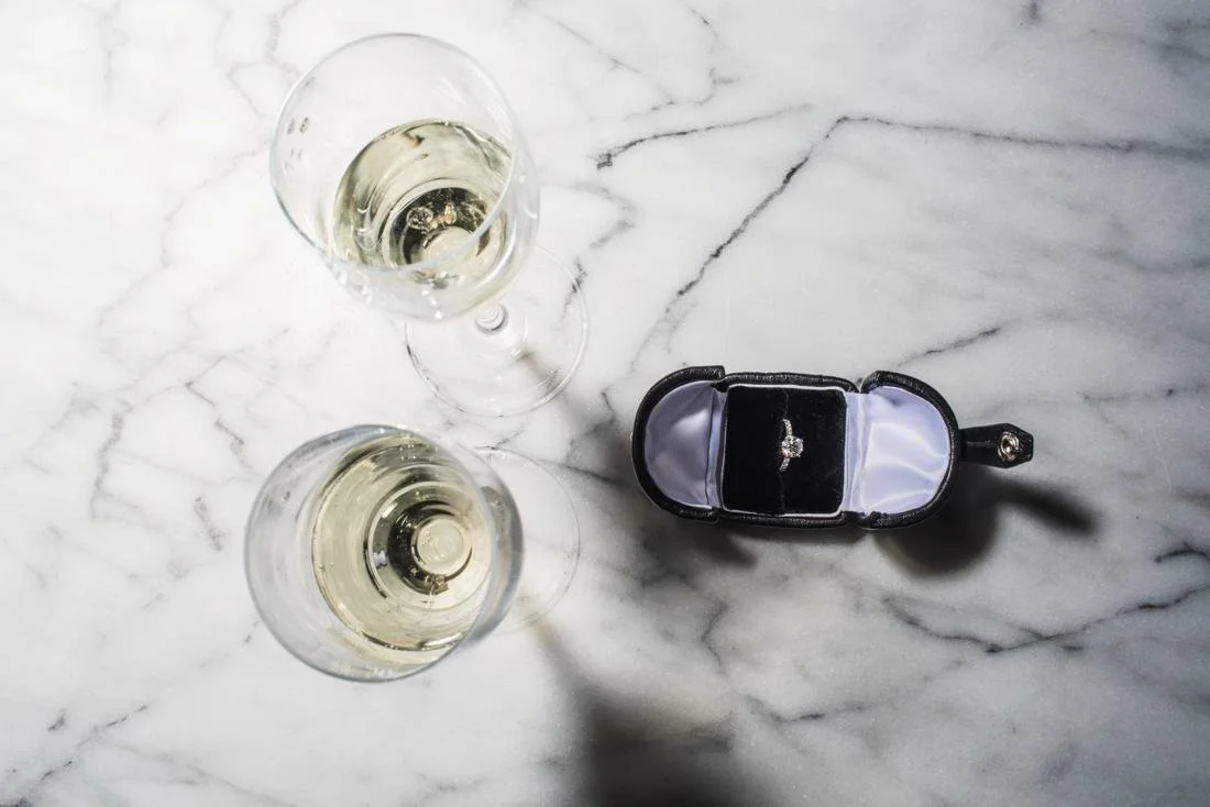 Detail of engagement ring and champagne glasses 