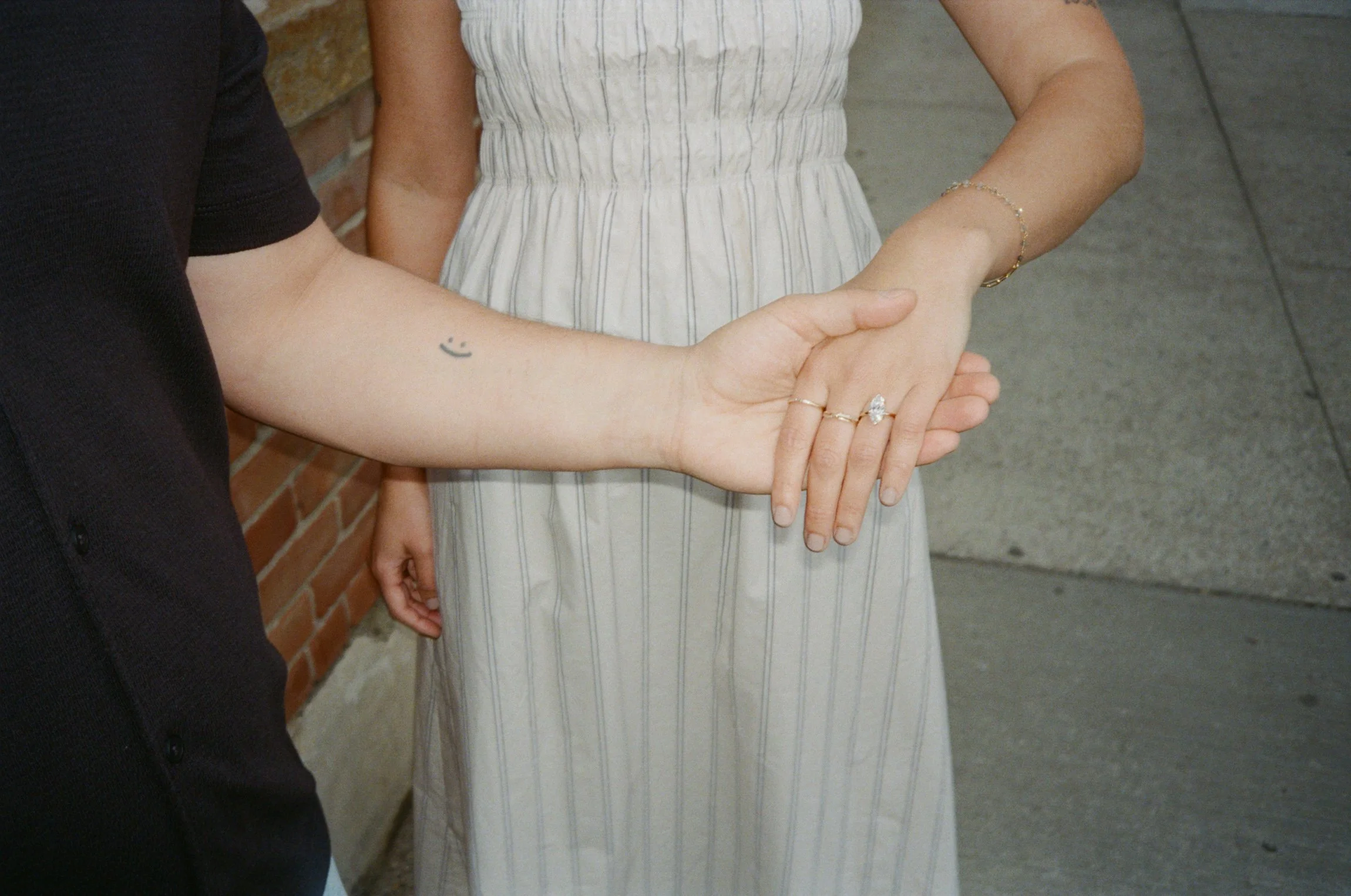 Close-up film photograph of a couple’s hands intertwined, showcasing an engagement ring during a romantic engagement session at Domino Park in Brooklyn.