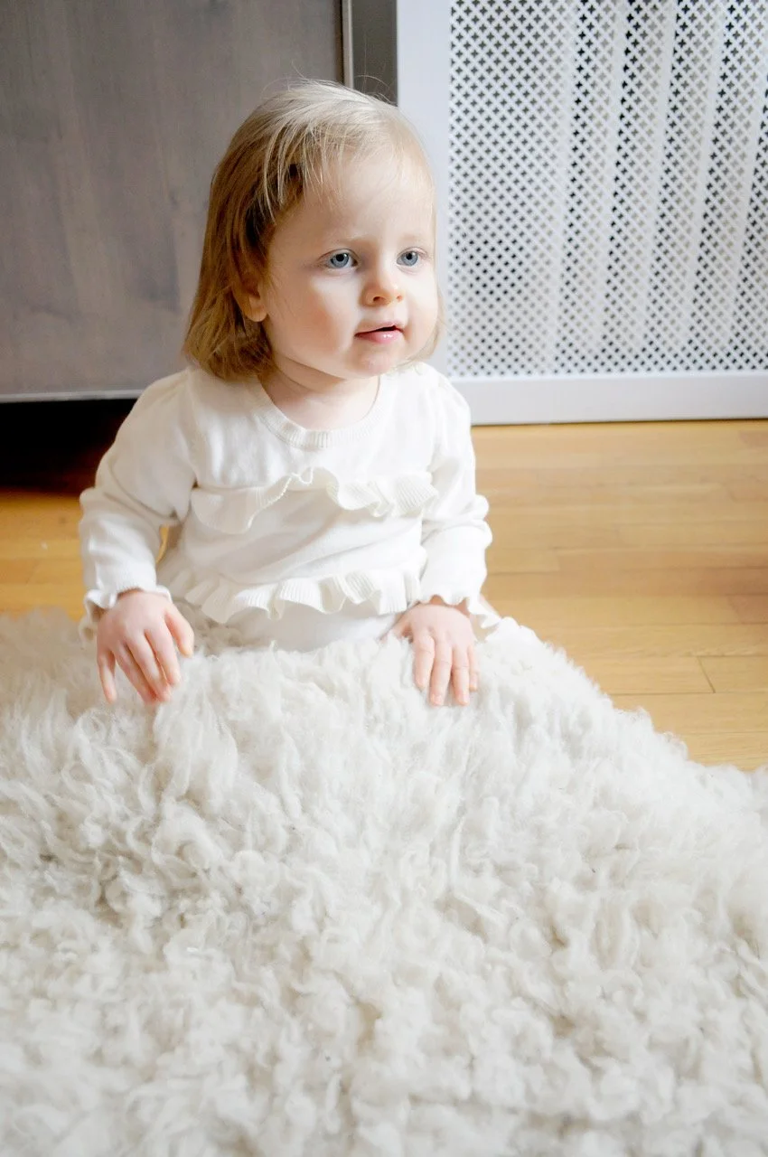 Little baby girl shot at home with a fuzzy sheep skin blanket.
