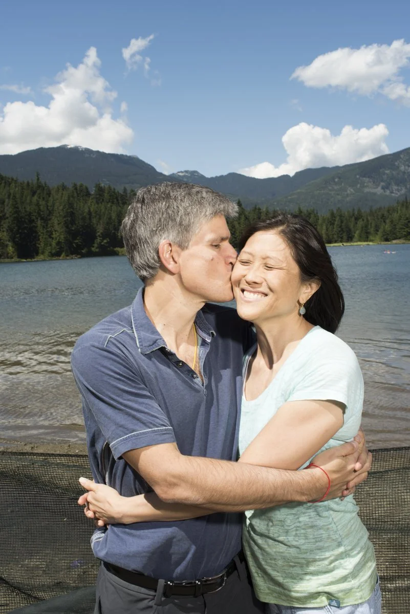 Mother and father embracing by a lake in Whistler during a family reunion