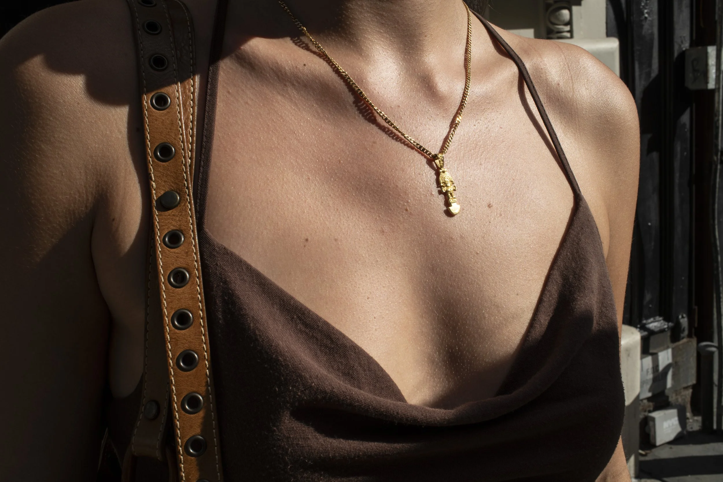 Person wearing a gold pendant during golden hour photographed on a New York street in Soho