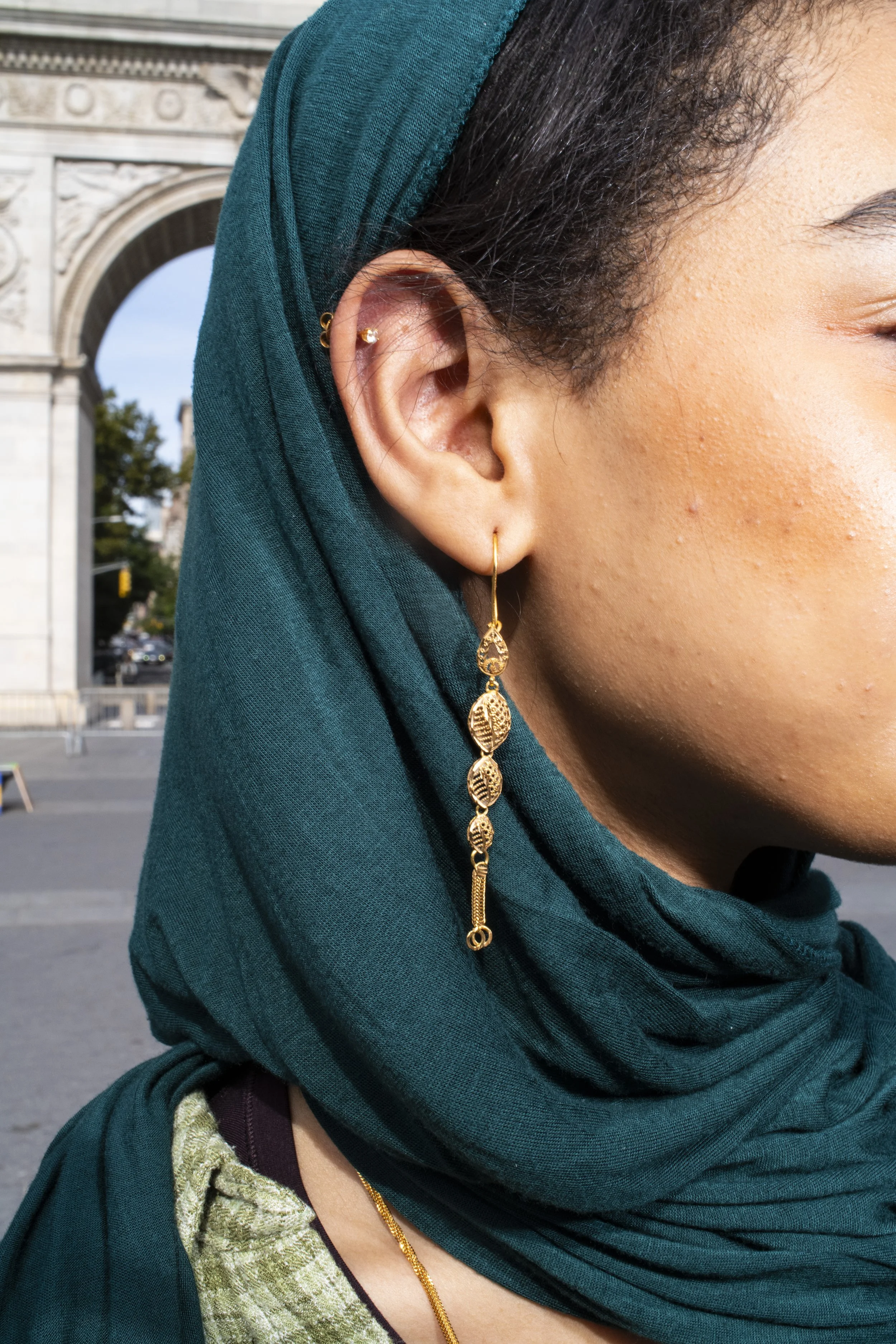 Hijabi woman wearing gold earrings and jewelry photographed on a New York City street