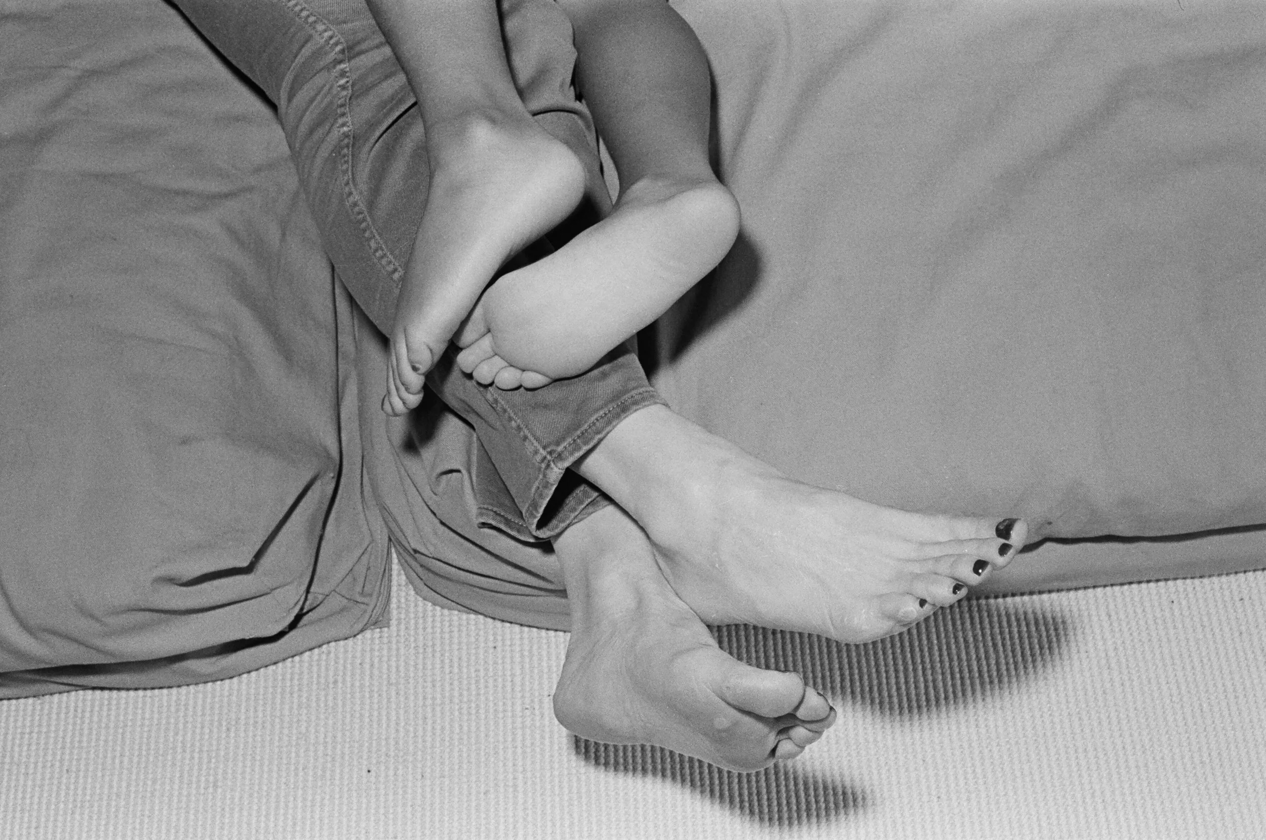 Candid lifestyle family photography of mother and daughter 's toes inside a  Manhattan townhouse. Shot with real black and white film.