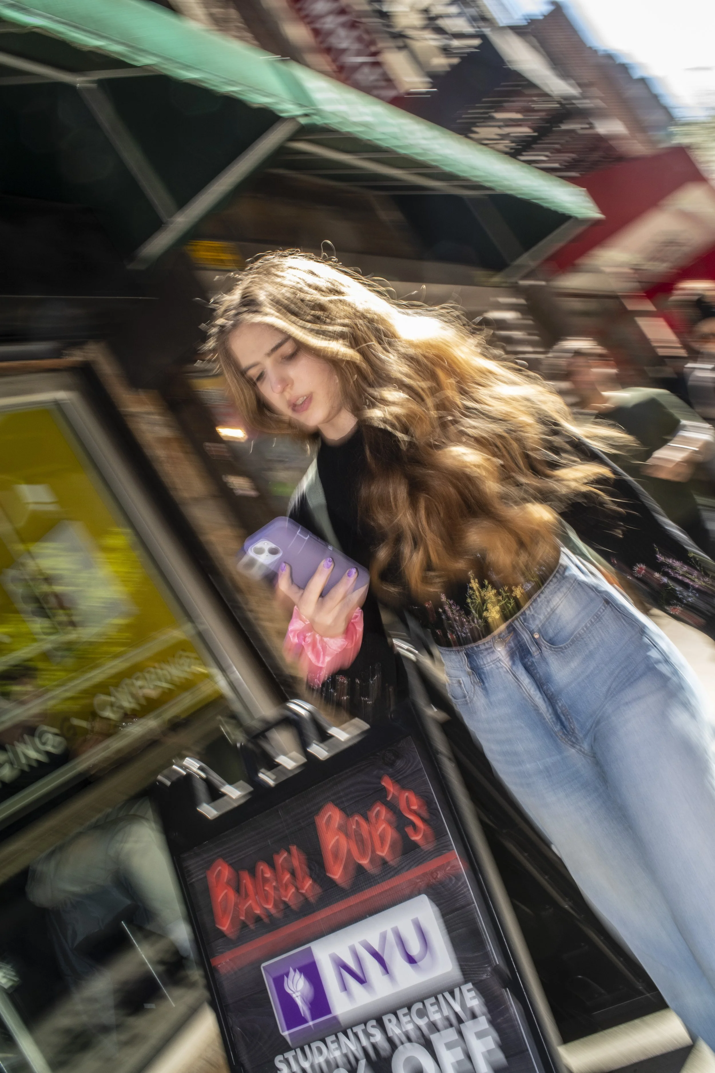 Color street photograph of a woman with long flowing hair looking at her phone