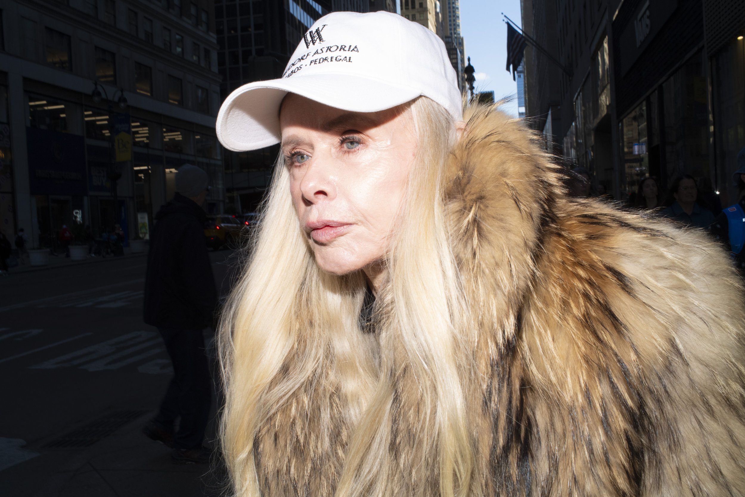 Color photograph of a woman in a fur coat and baseball cap