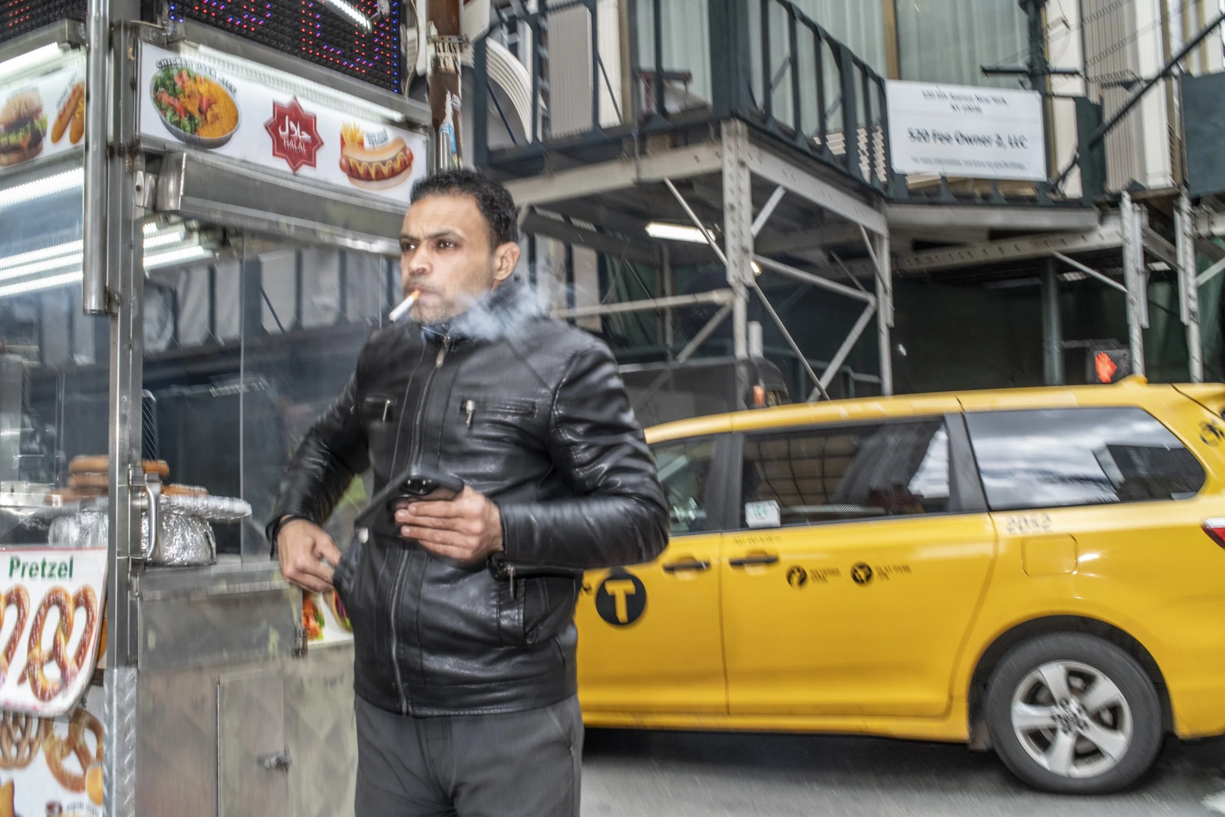 Color photograph of a man in a leather jacket smoking a cigarette