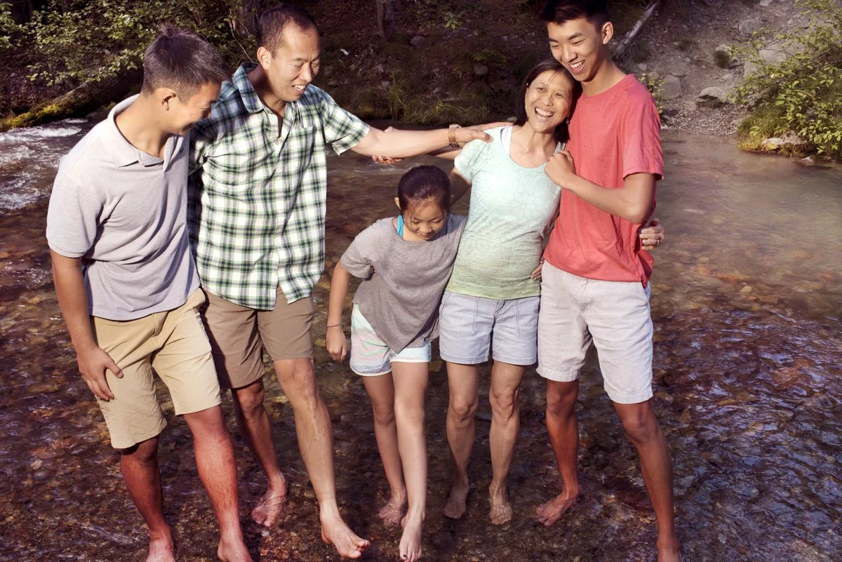Aunt, uncle and three cousins goofing around barefoot in a creek in Whistler