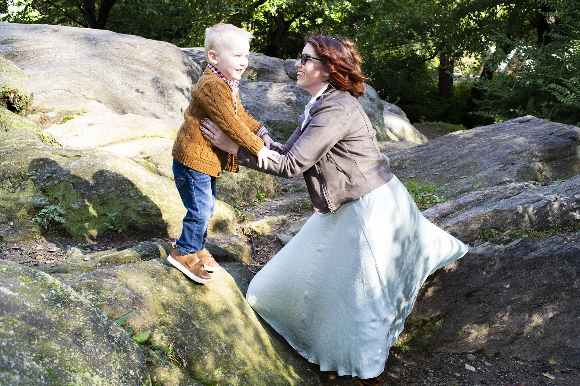 Family portrait session of a baby playing with mom on big rocks in Central Park by Angela Cappetta. 