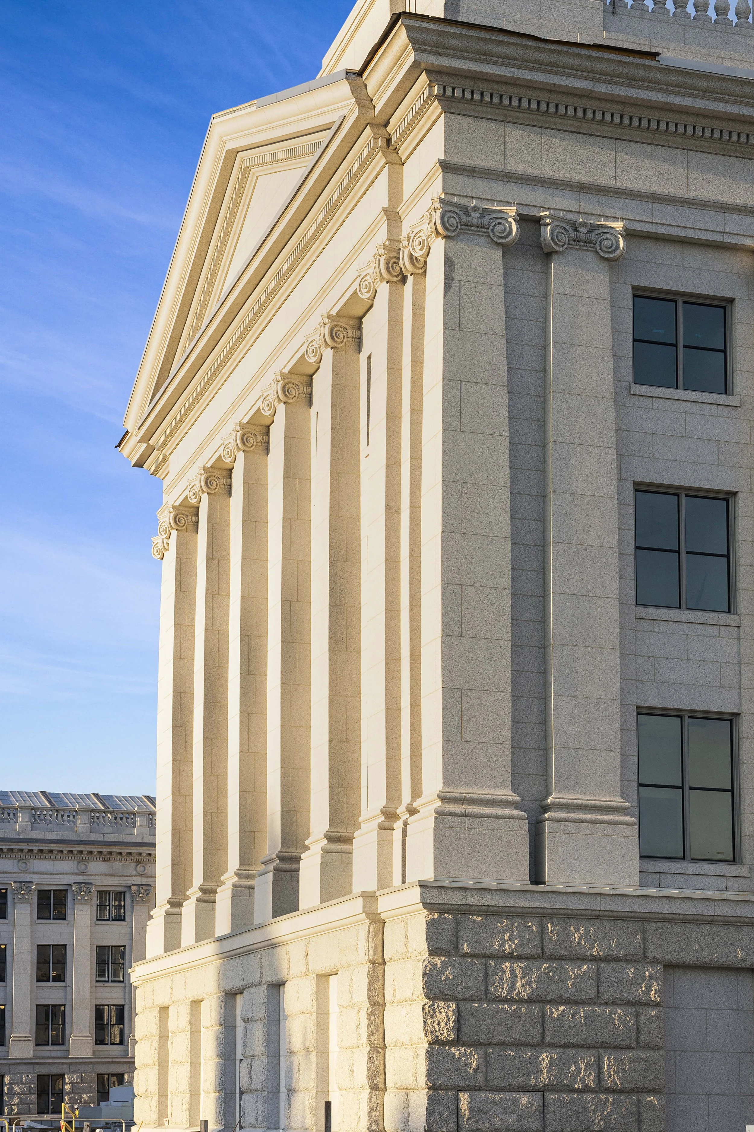Close-up of a neoclassical building with columns and decorative architectural details, with a blue sky in the background.