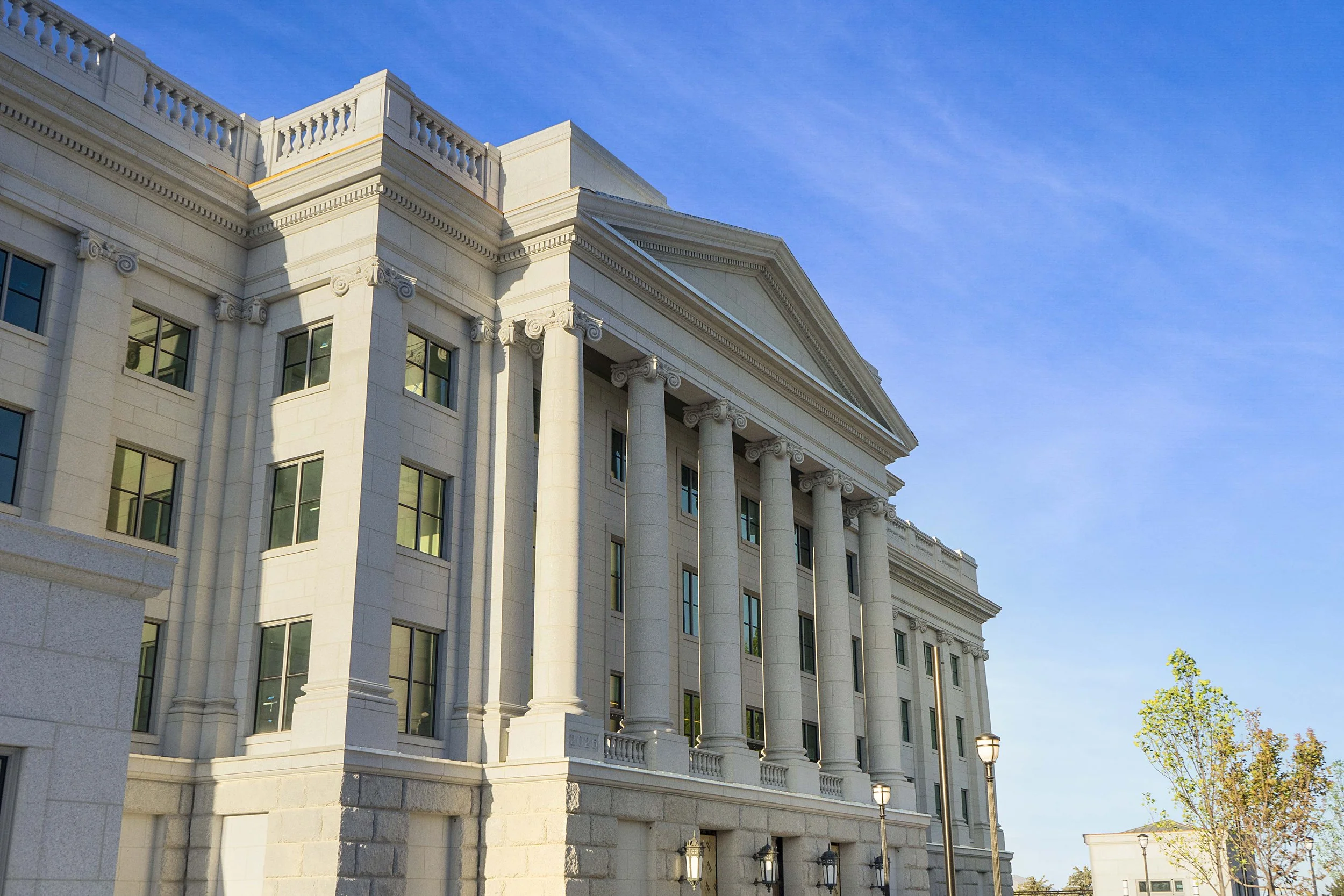 A neoclassical building with tall columns, large windows, and ornate architectural details under a blue sky.