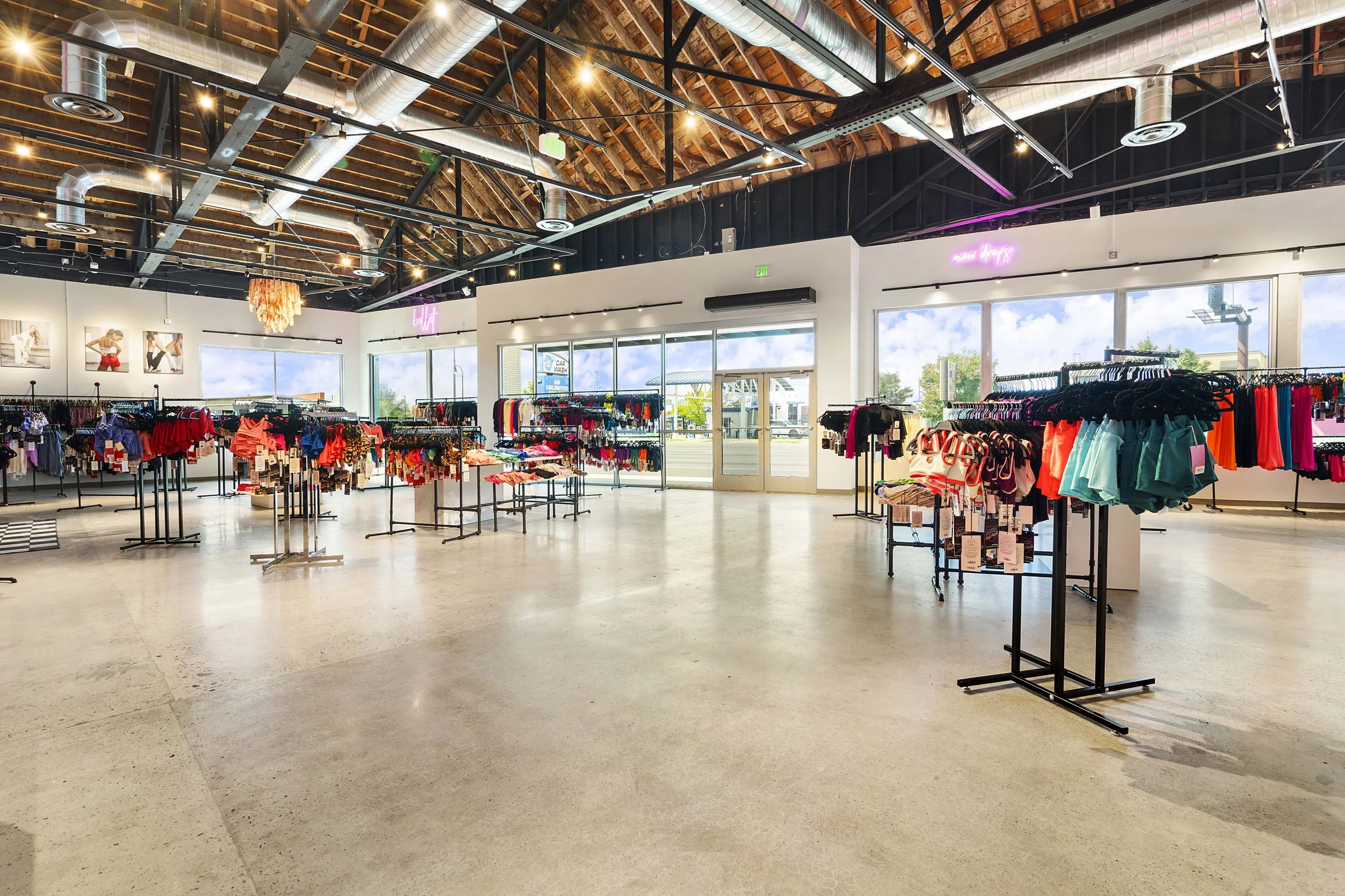 Interior of a clothing store with racks of colorful athletic wear and large windows.