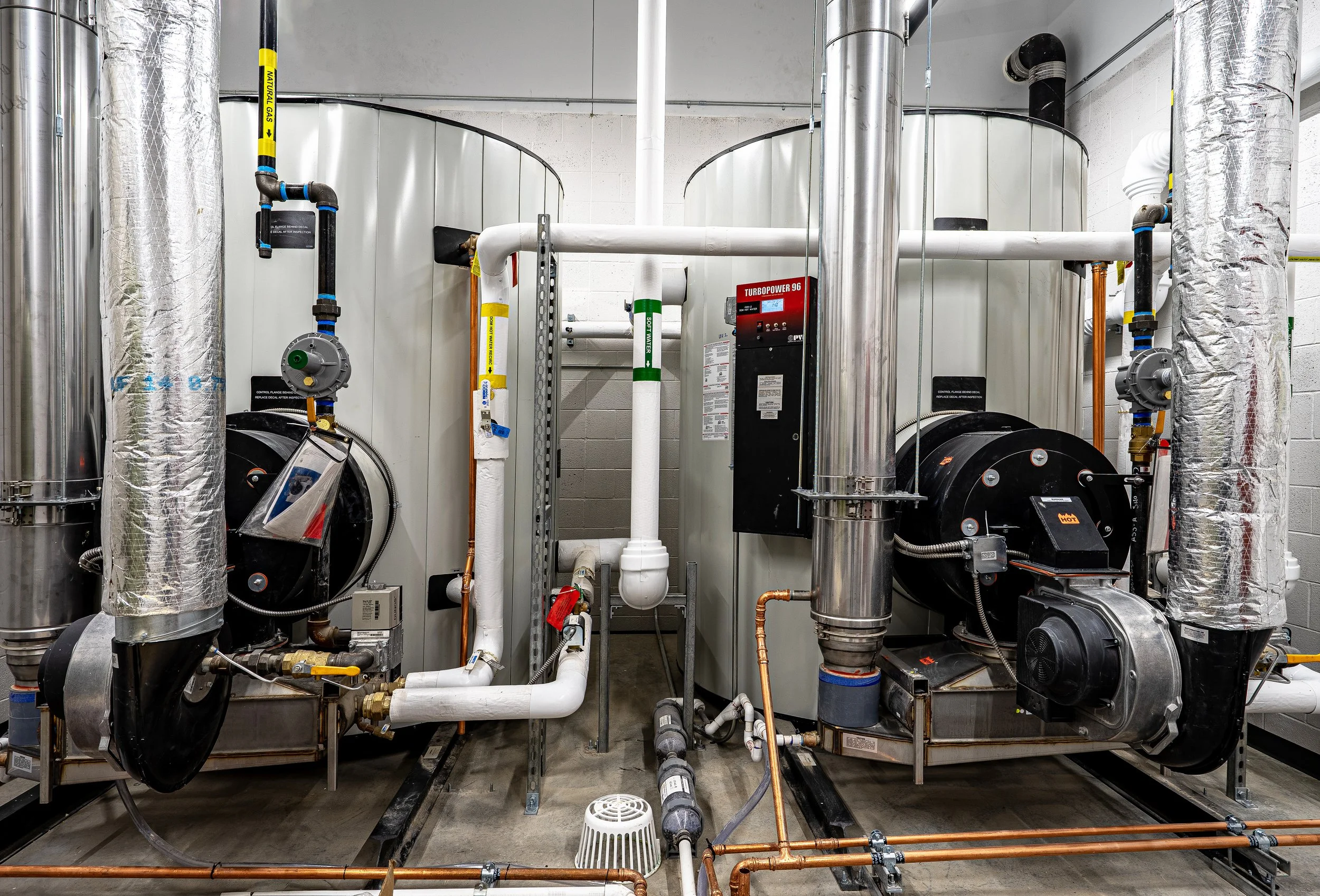 Industrial HVAC system with large metal tanks, insulated pipes, valves, and control panels.