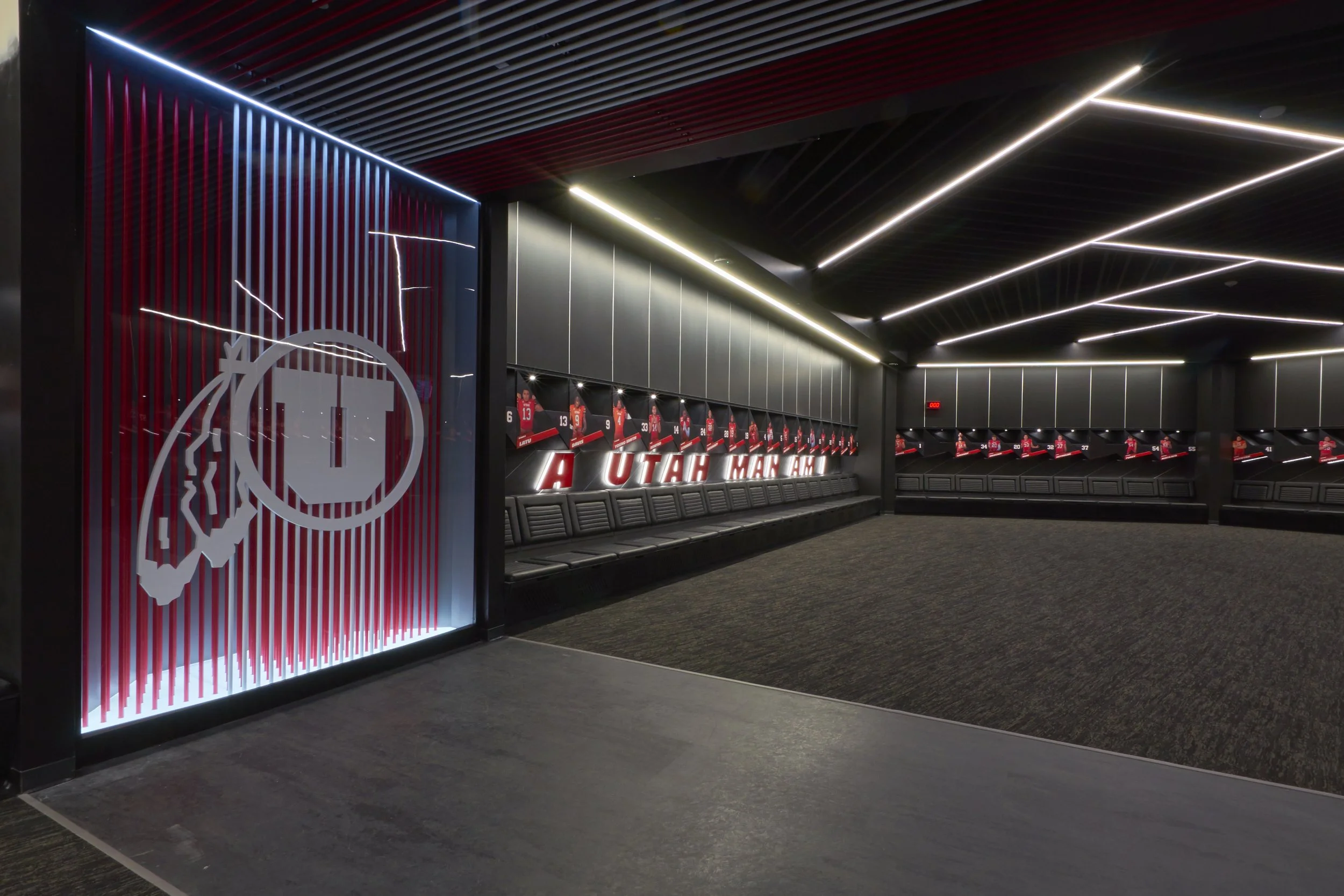 Empty hockey locker room with seats, team logos, and hockey players on display.