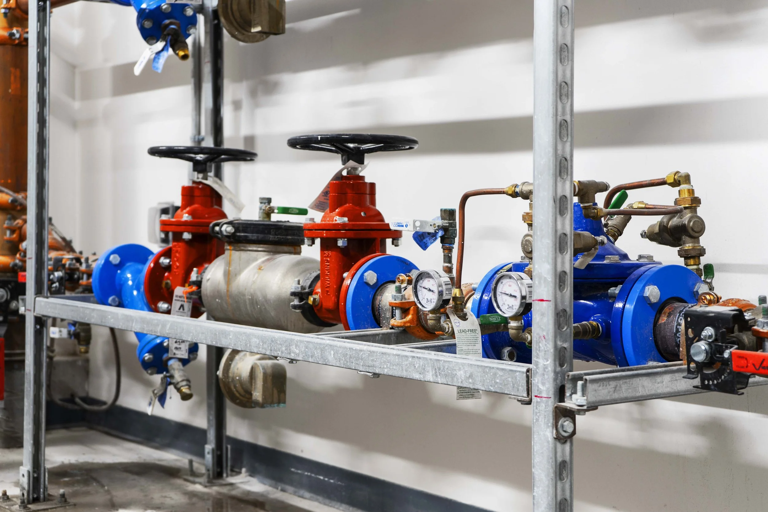 Industrial plumbing system with gauges, valves, and pipes mounted on a metal frame.
