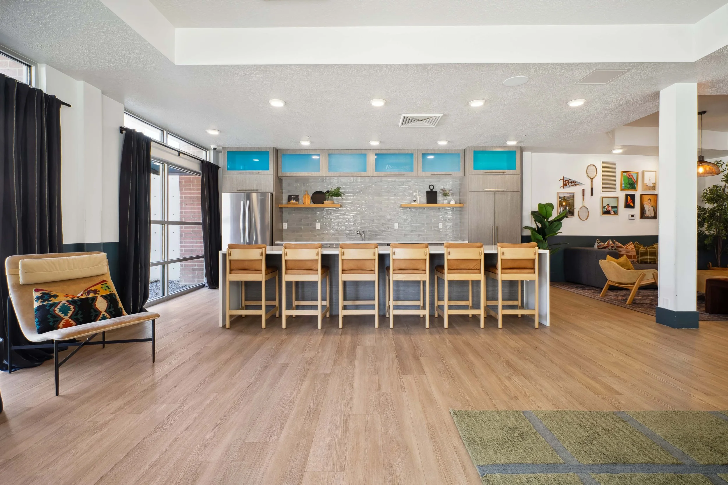 Open-concept kitchen and living room area with a kitchen island, bar stools, and gallery wall decor.